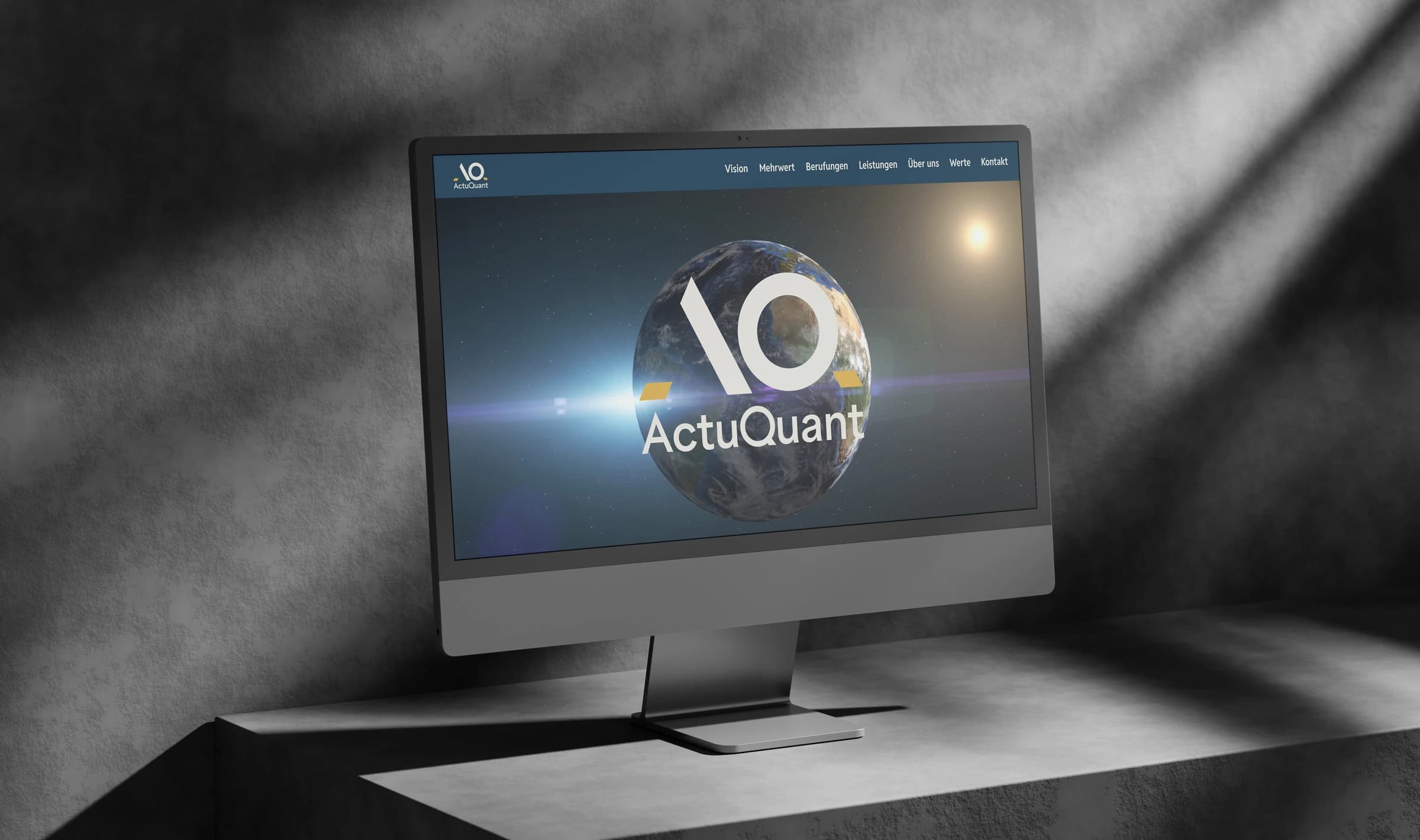 Ein iMac auf einem hellen Sockel zeigt die Startseite von ActuQuant: das Logo vor der Erde aus dem Weltall, darüber die Navigation.