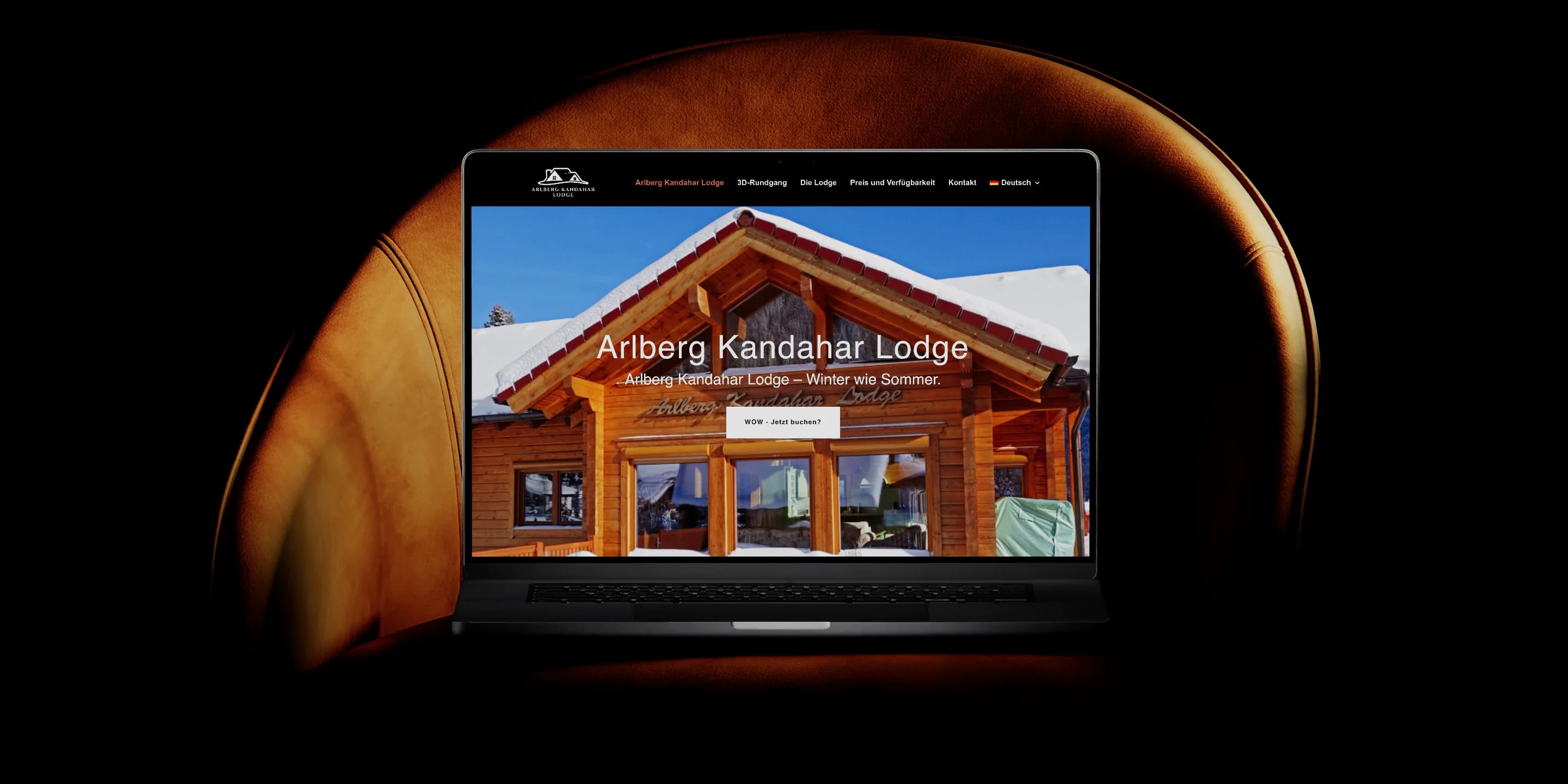 Webentwicklung für die Arlberg Kandahar Lodge: Ein MacBook zeigt die Startseite von arlbergkandaharlodge.at mit dem verschneiten Holzchalet und dem Schriftzug Arlberg Kandahar Lodge.