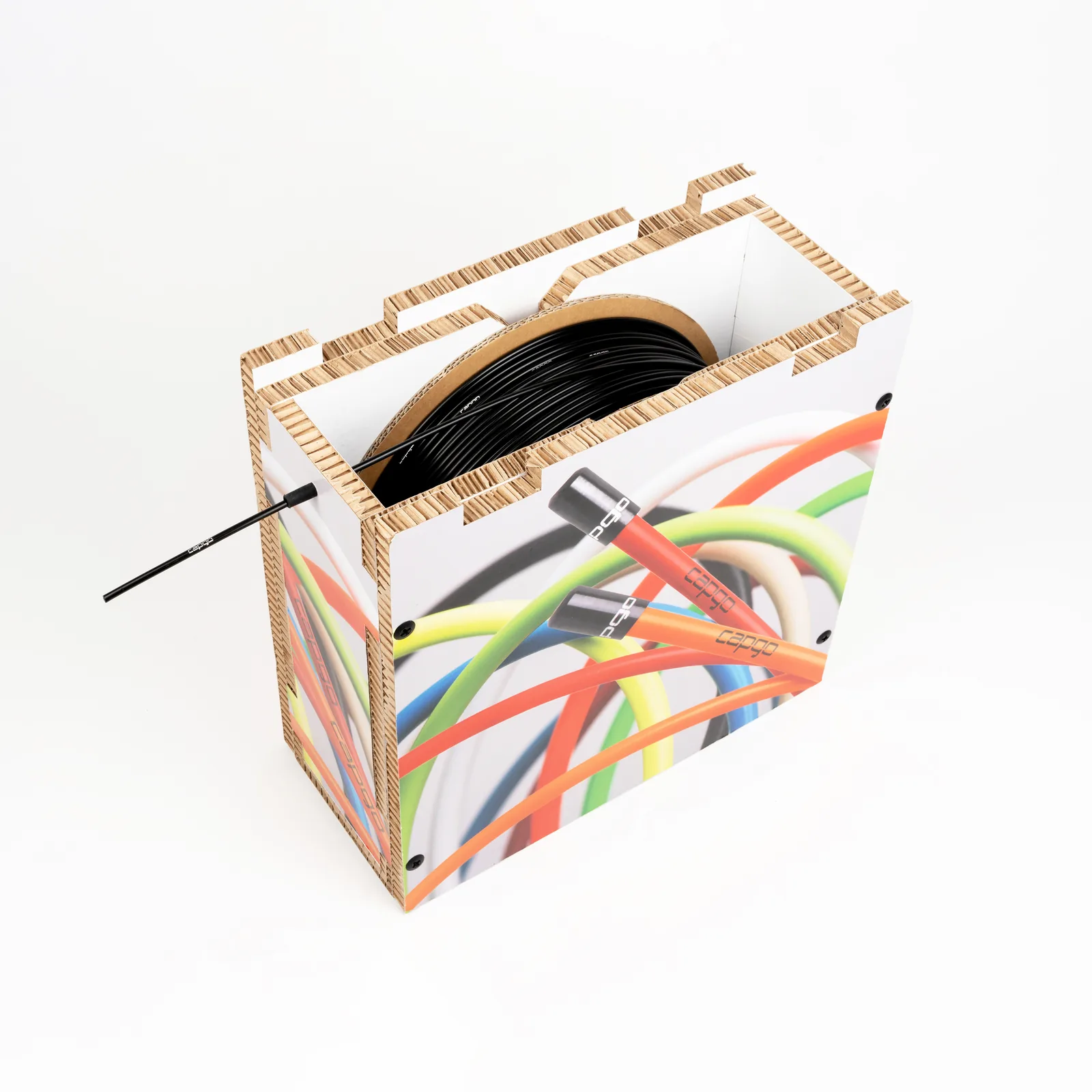 Eine geöffnete Werkstattbox aus Karton mit bunt bedruckten Seiten und einer schwarzen Außenhülle auf der Rolle, freigestellt vor grauem Grund.