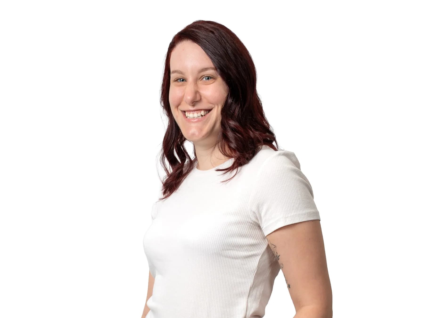 Stefanie Fleidl mit langen dunkelroten Haaren lacht vor weißem Grund, in weißem Shirt.