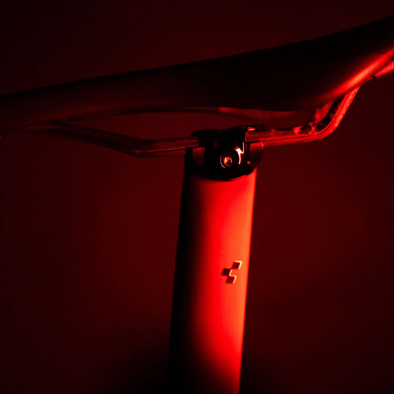 Sattel und Sattelstütze von der Seite, die Stütze mit dem CUBE-Zeichen rot angestrahlt, der Hintergrund schwarz.