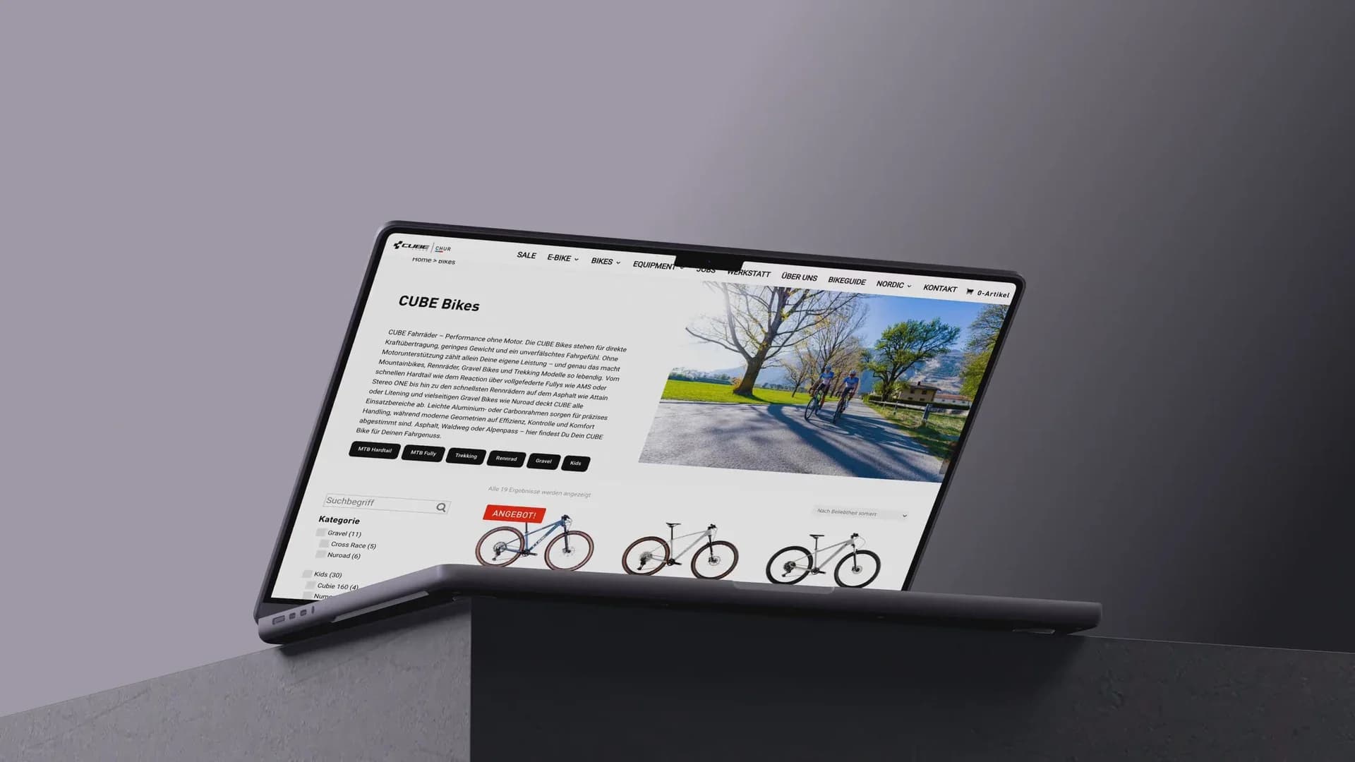 Ein MacBook auf einem Betonsockel zeigt eine Bike-Übersicht aus dem Online-Shop des CUBE STORE CHUR.