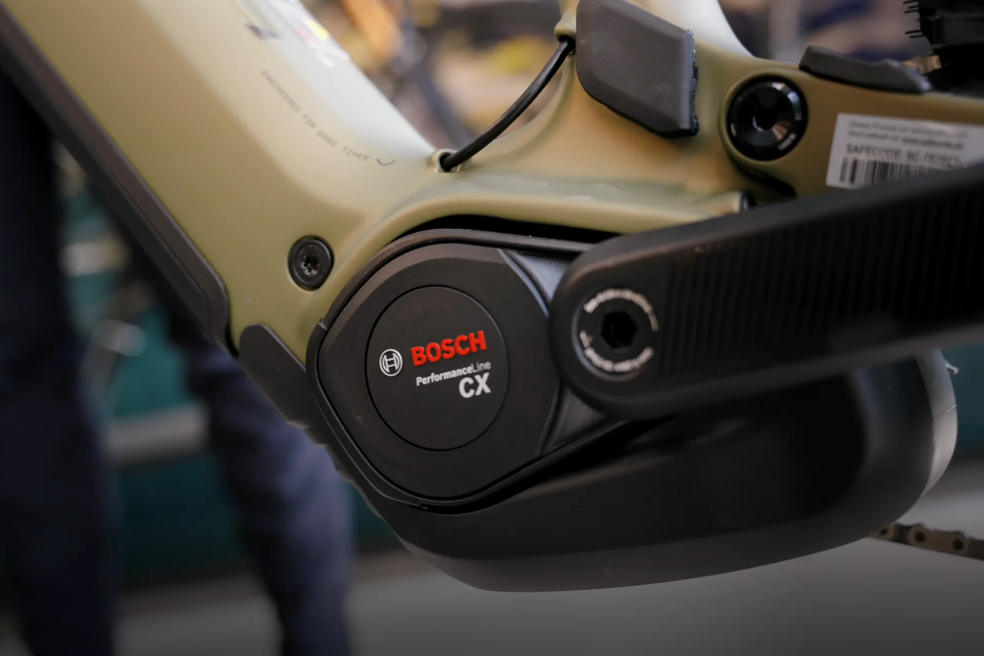Standbild aus dem Film über das Bosch-Update: Nahaufnahme des Antriebs an einem olivgrünen E-Mountainbike mit dem Schriftzug Bosch Performance Line CX.