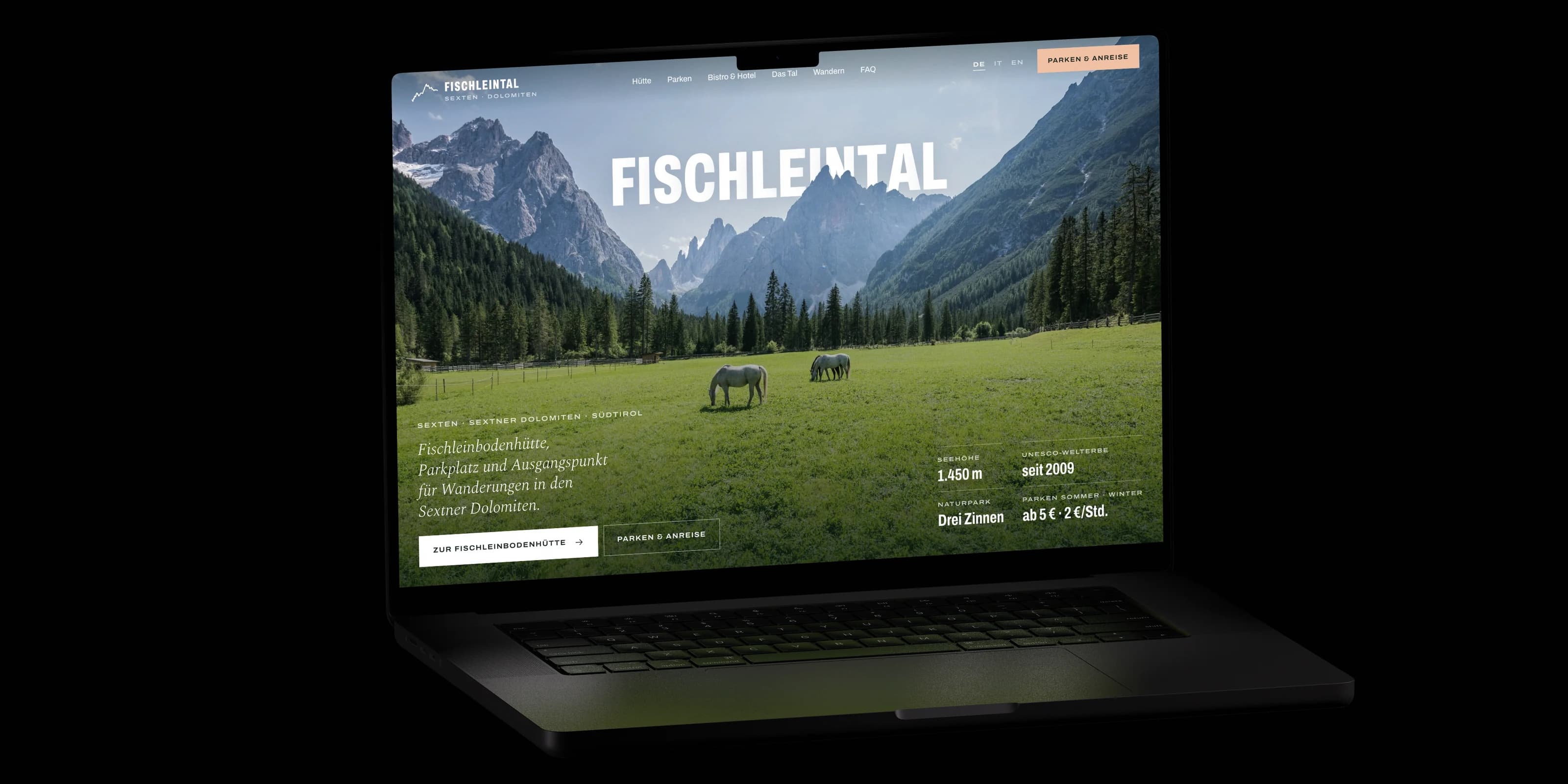 Ein aufgeklapptes MacBook im Dunkeln zeigt die Startseite von fischleintal-dreizinnen.it: der Schriftzug Fischleintal zwischen Himmel und Bergen, darunter eine Wiese mit zwei Pferden.
