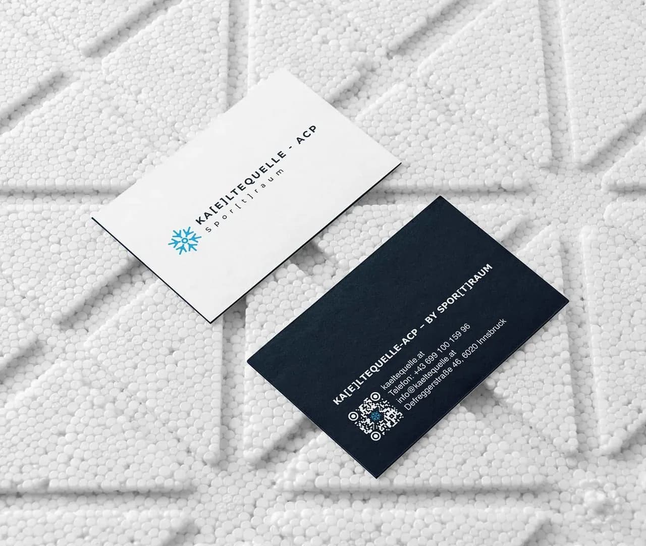 Zwei Visitenkarten auf weißem Untergrund: vorne die Wortmarke in Dunkelblau auf Weiß, hinten Kontaktdaten und ein QR-Code in Weiß auf Dunkelblau.