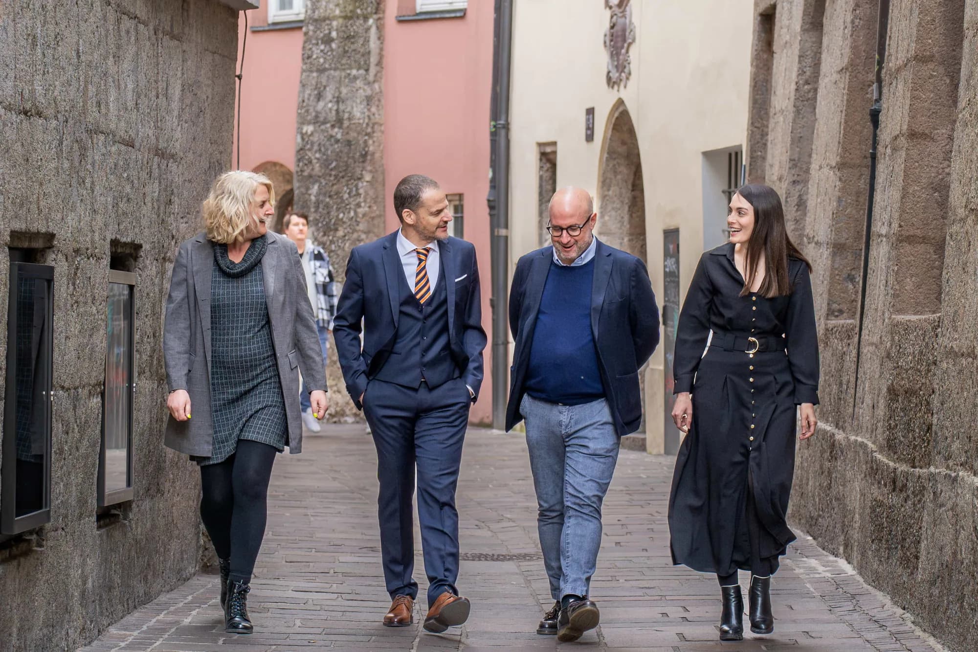 Das Team der Kanzlei geht von der Kamera weg eine schmale Altstadtgasse hinunter, links und rechts alte Fassaden mit Laternen.