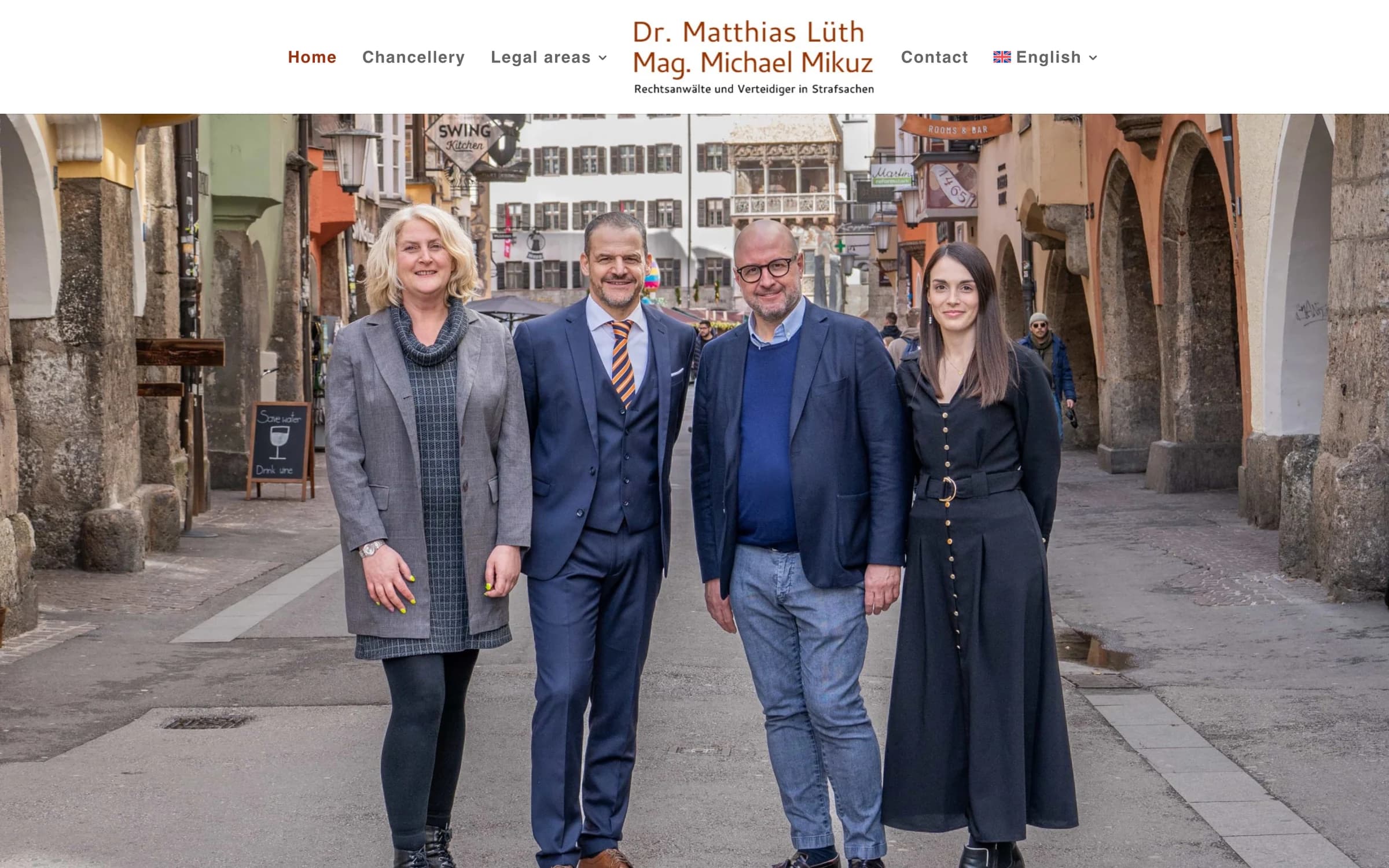 Die englische Fassung derselben Startseite: gleiche Anordnung und gleiches Teamfoto, die Navigation liest Home, Chancellery, Legal areas und Contact.