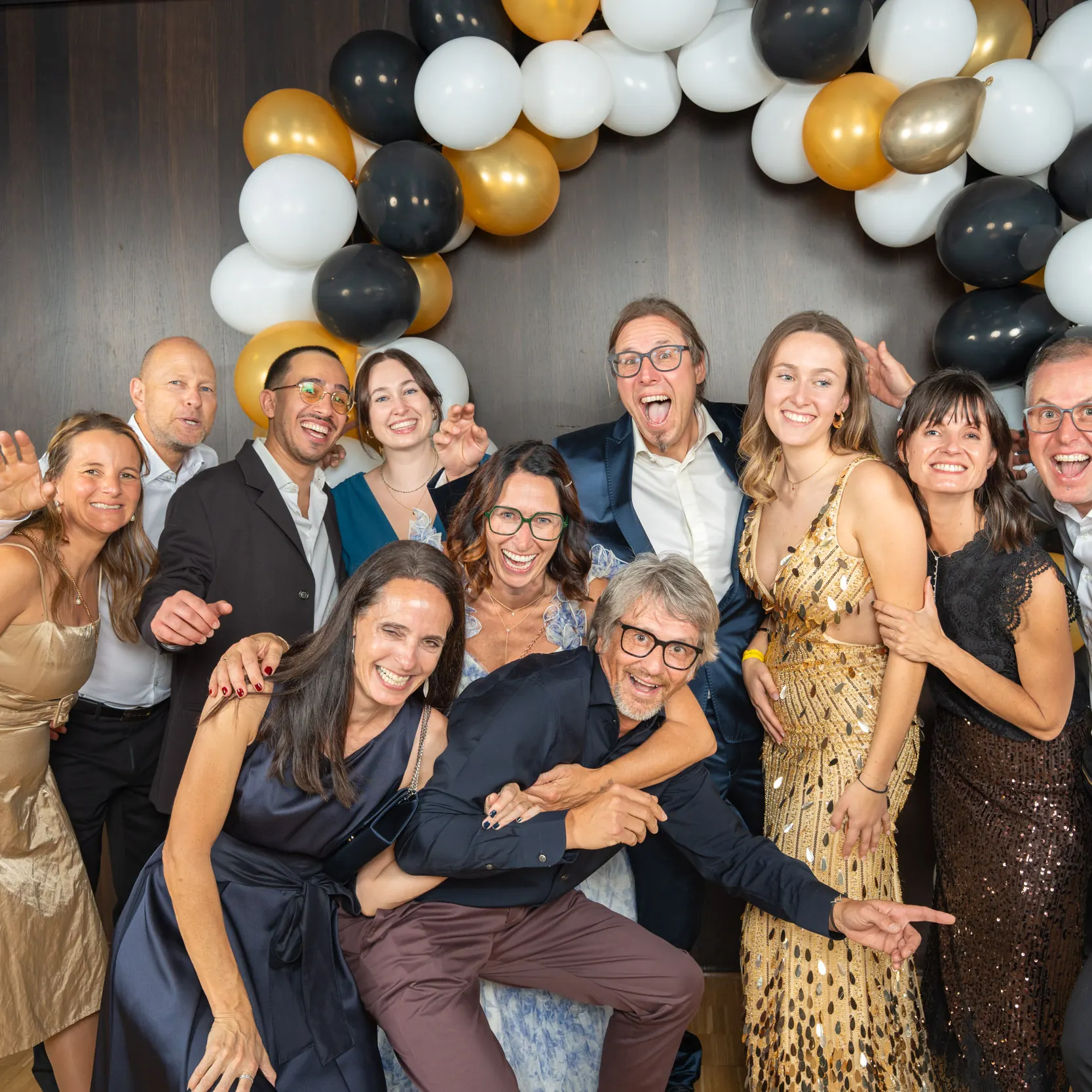 Eine ausgelassene Runde in Gold, Schwarz und Weiß albert vor dem Ballonbogen herum
