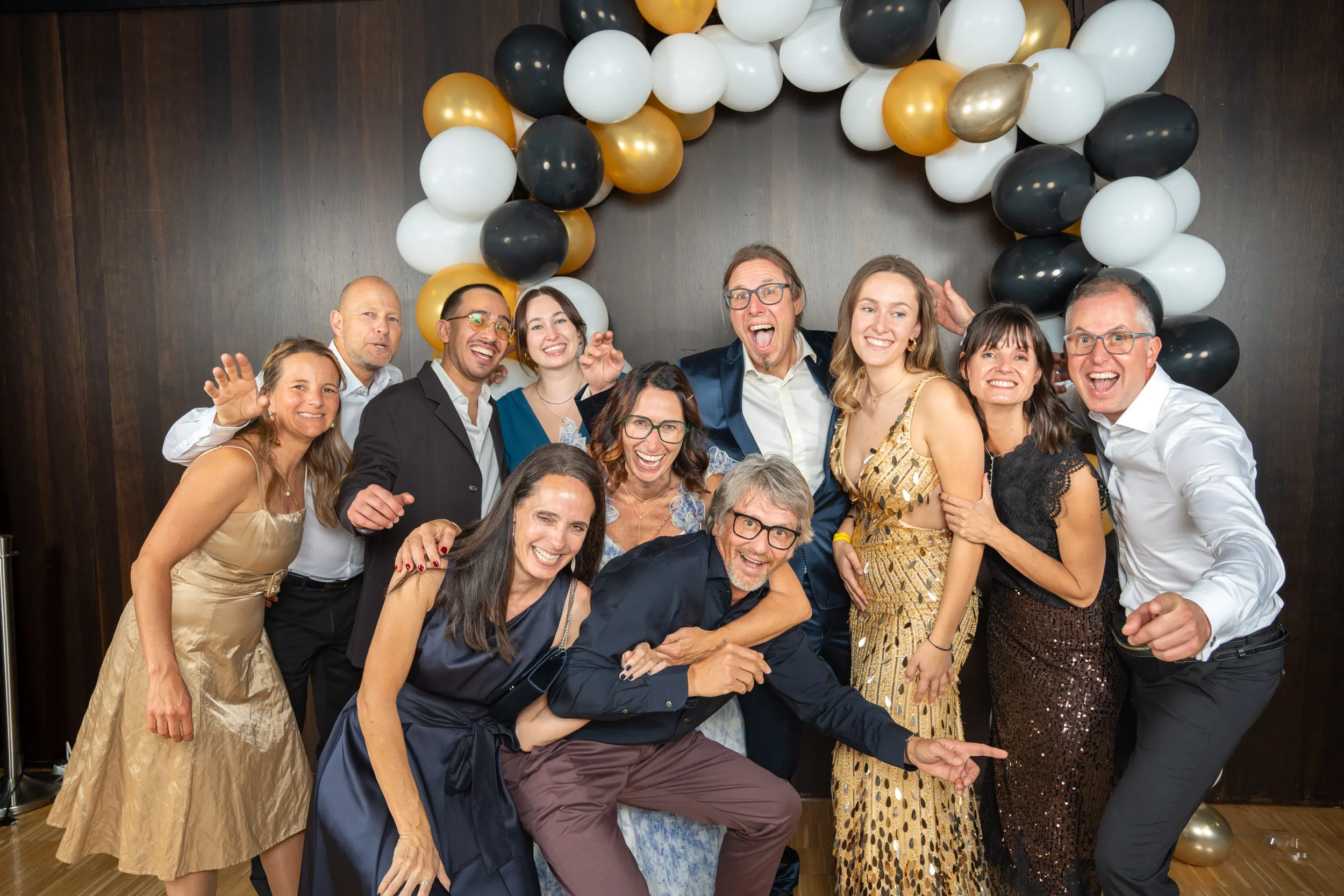 Eine ausgelassene Runde in Gold, Schwarz und Weiß albert vor dem Ballonbogen herum