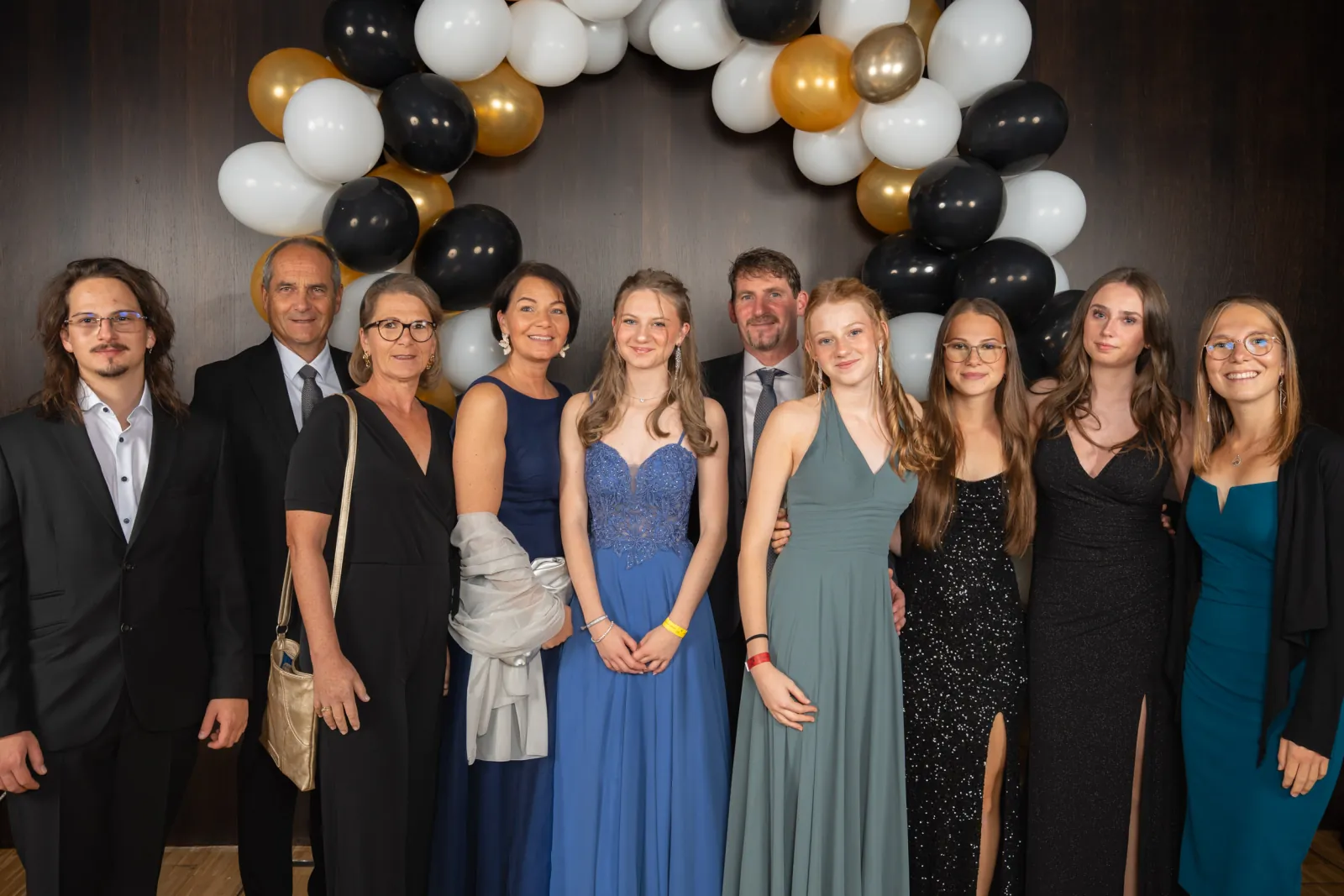 Eine große Runde aus Schülerinnen, Schülern und Eltern in Abendgarderobe