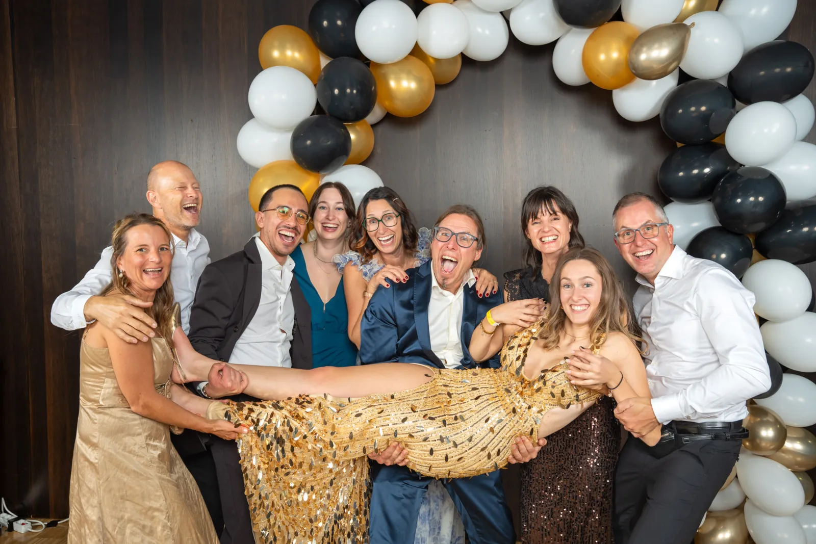 Eine ausgelassene Runde hält eine Frau im goldenen Paillettenkleid quer