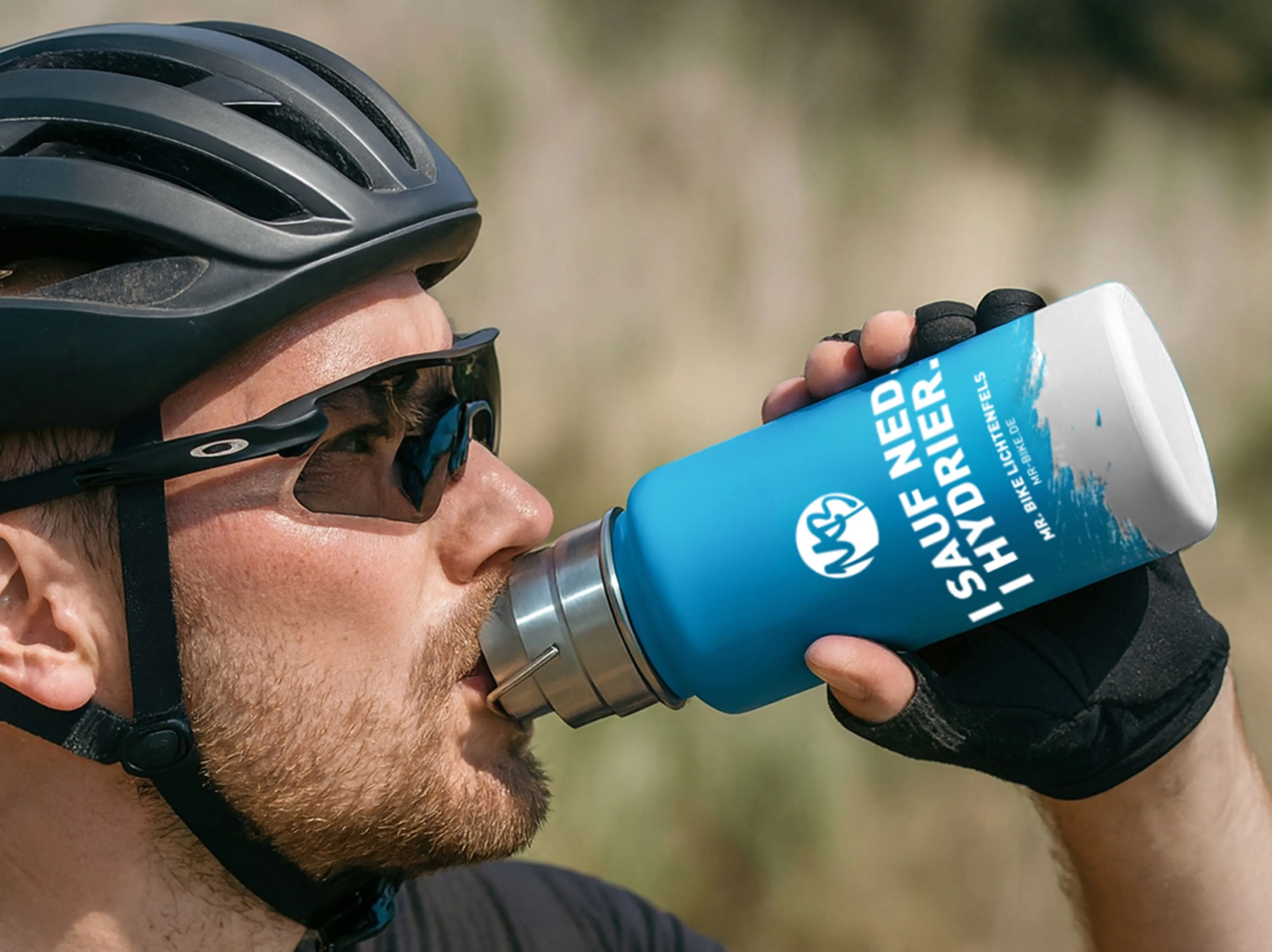 Ein Rennradfahrer mit Helm und Sonnenbrille trinkt aus der blauen Mr. Bike Trinkflasche mit MB-Signet, dem Schriftzug Mr. Bike Lichtenfels und der Adresse mr-bike.de.