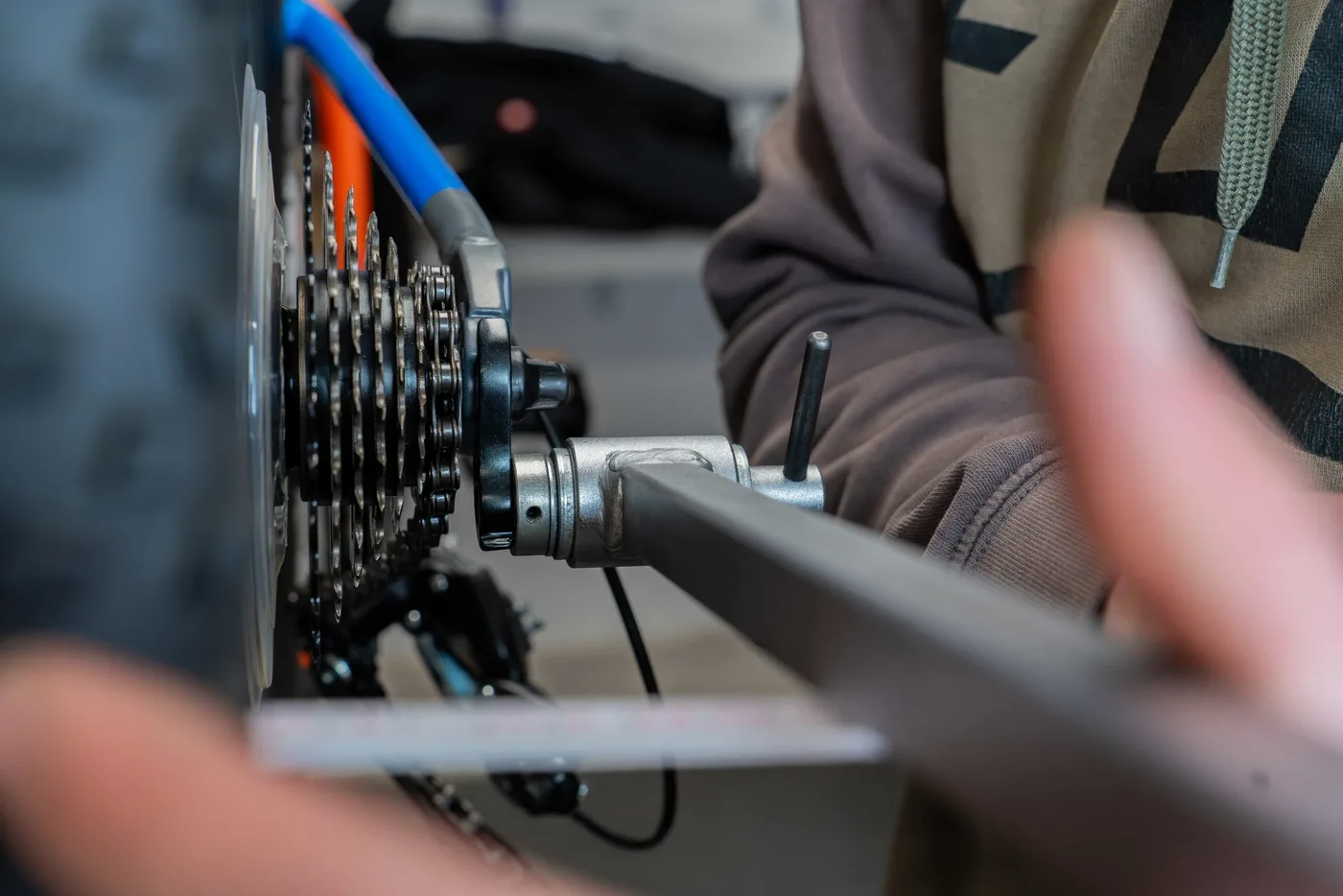 Nahaufnahme einer Hand, die mit einem Werkzeug an der Kassette eines Hinterrads arbeitet.