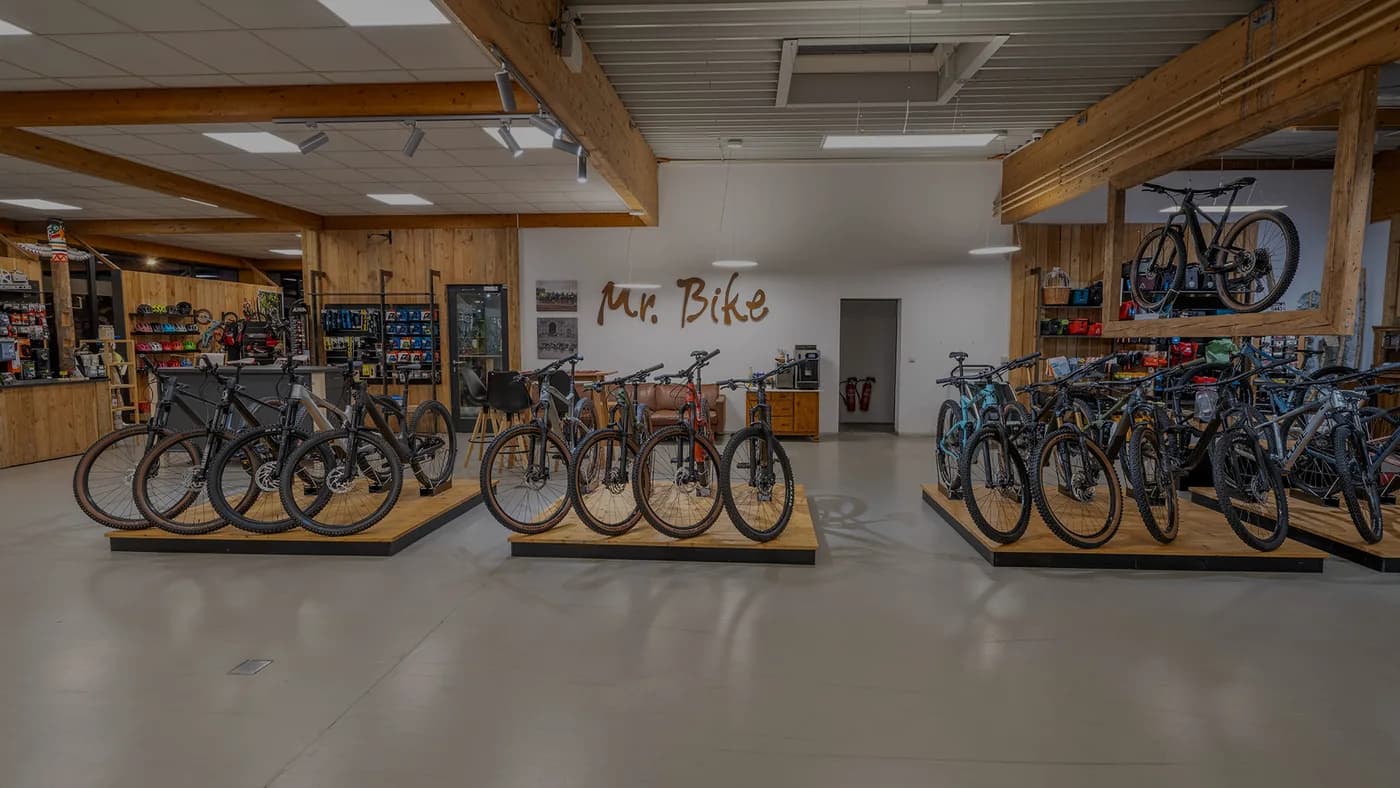 Der Verkaufsraum von Mr. Bike: Bikes auf Holzpodesten unter Holzbalken, an der Wand der Schriftzug Mr. Bike.