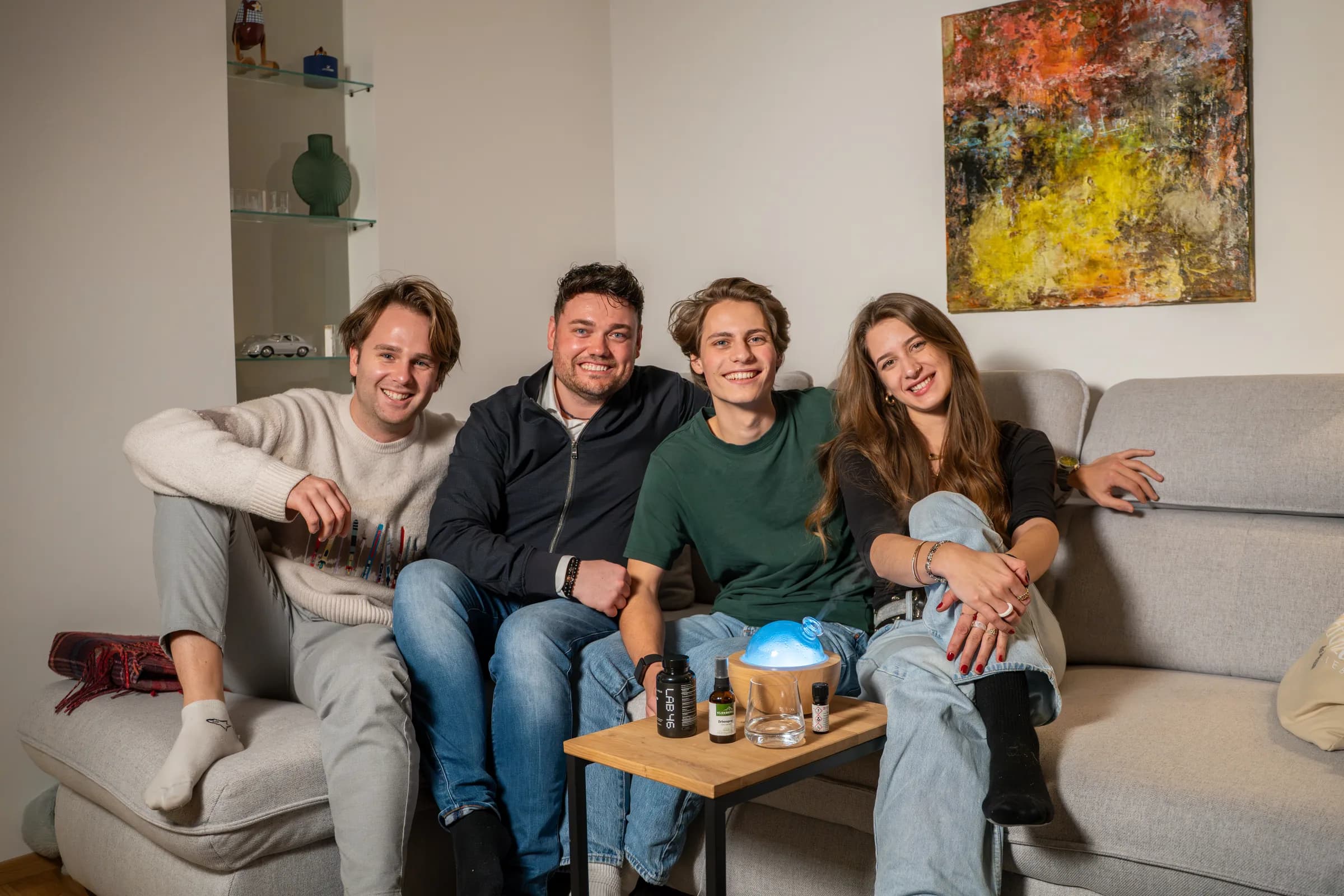 Vier Personen sitzen nebeneinander auf einem Sofa, vor ihnen auf dem Tisch der leuchtende Diffuser und die Öle.