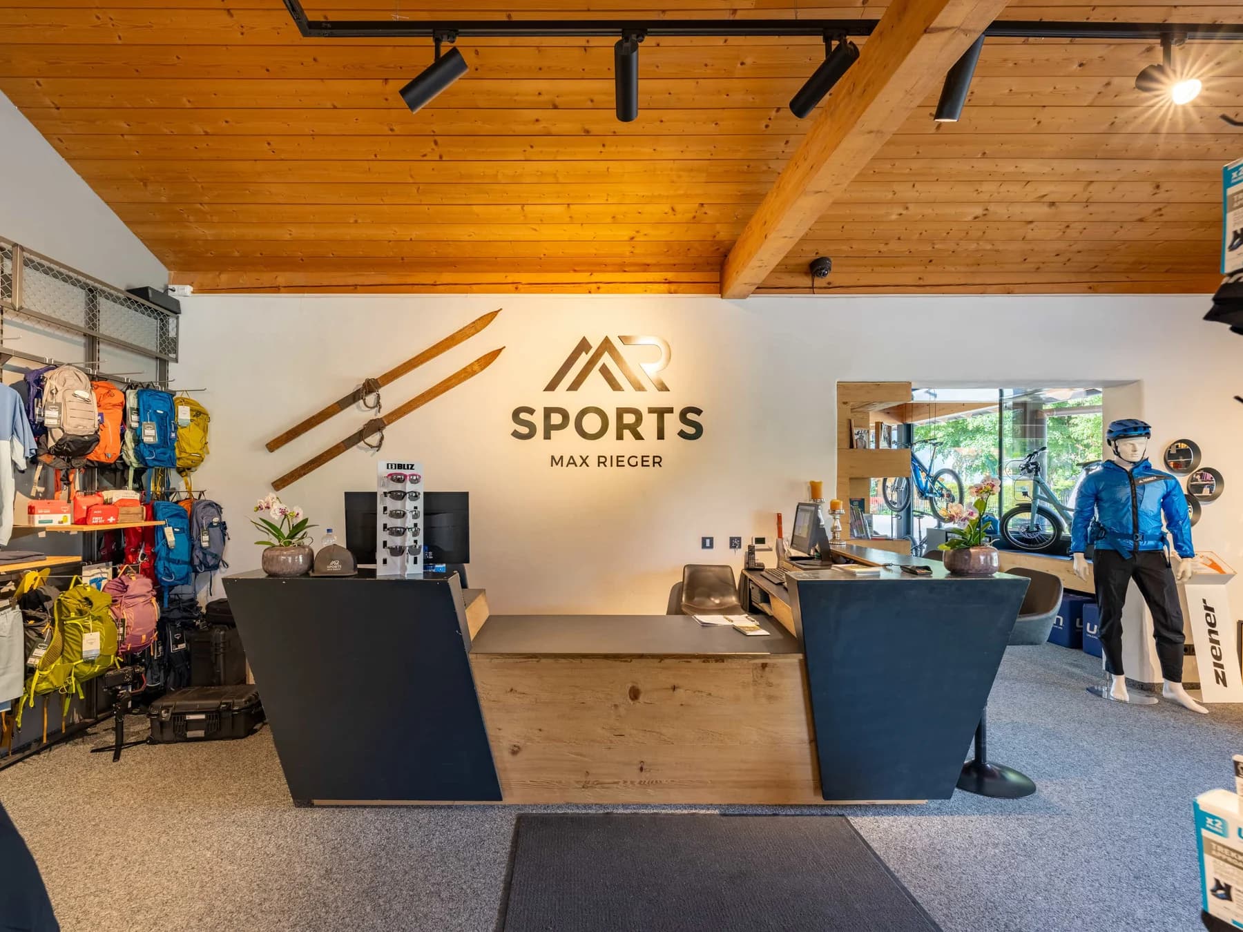 Die Theke des Sportgeschäfts unter der Holzdecke, darüber der Schriftzug MR Sports an der Wand.