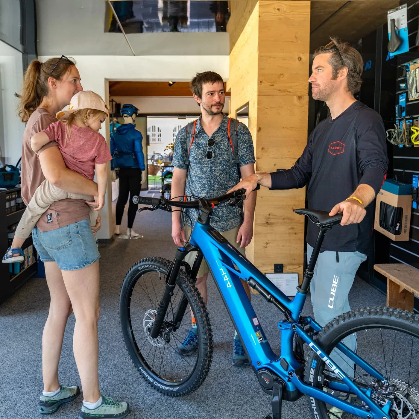 Ein Mitarbeiter erklärt einer Familie ein blaues E-Mountainbike im Verkaufsraum.