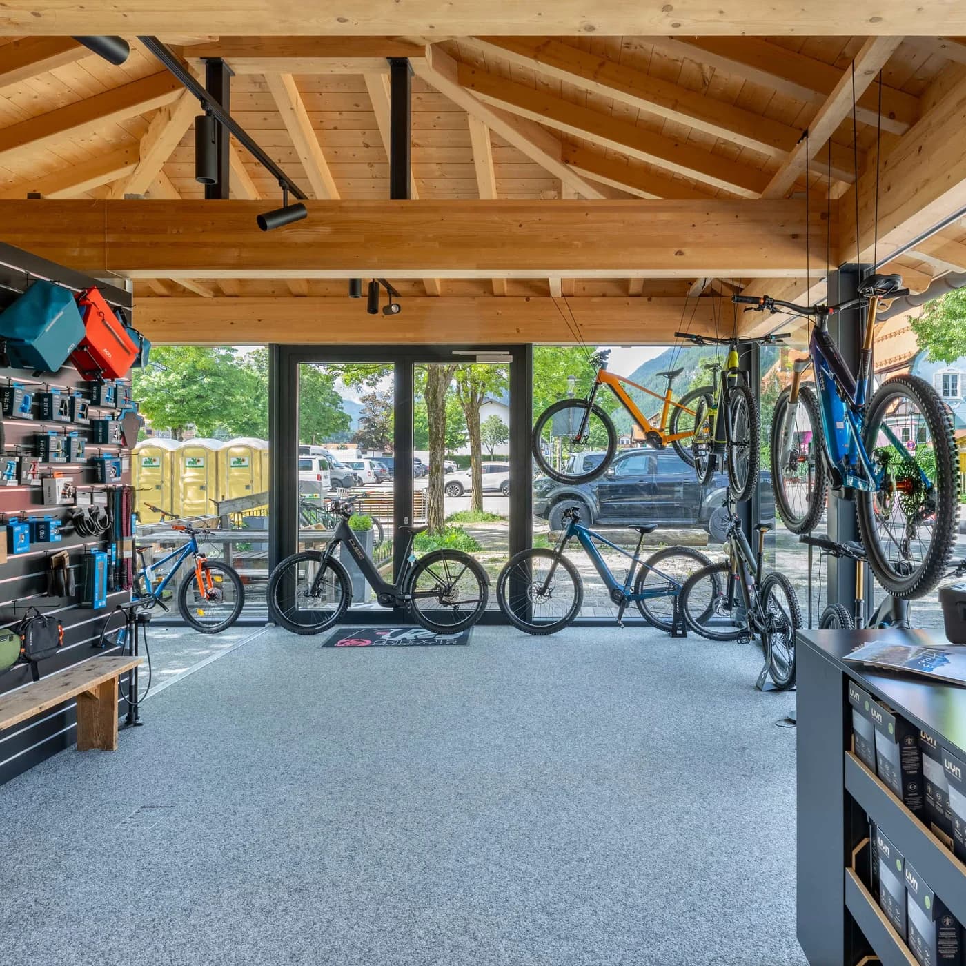 Der offene Verkaufsraum des Bikecenters unter einer Holzdecke, Mountainbikes in einer Reihe vor der Glasfront.