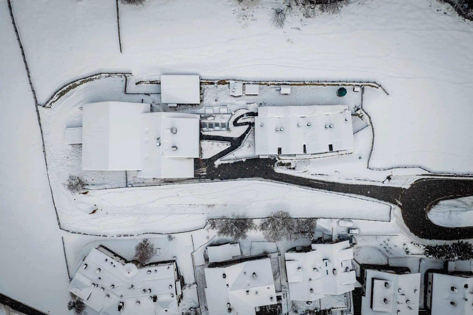 Der Stabinger Hof senkrecht von oben im Schnee: die Dächer von Bauernhaus und Chalets, die Wege und die Grenze des Grundstücks.