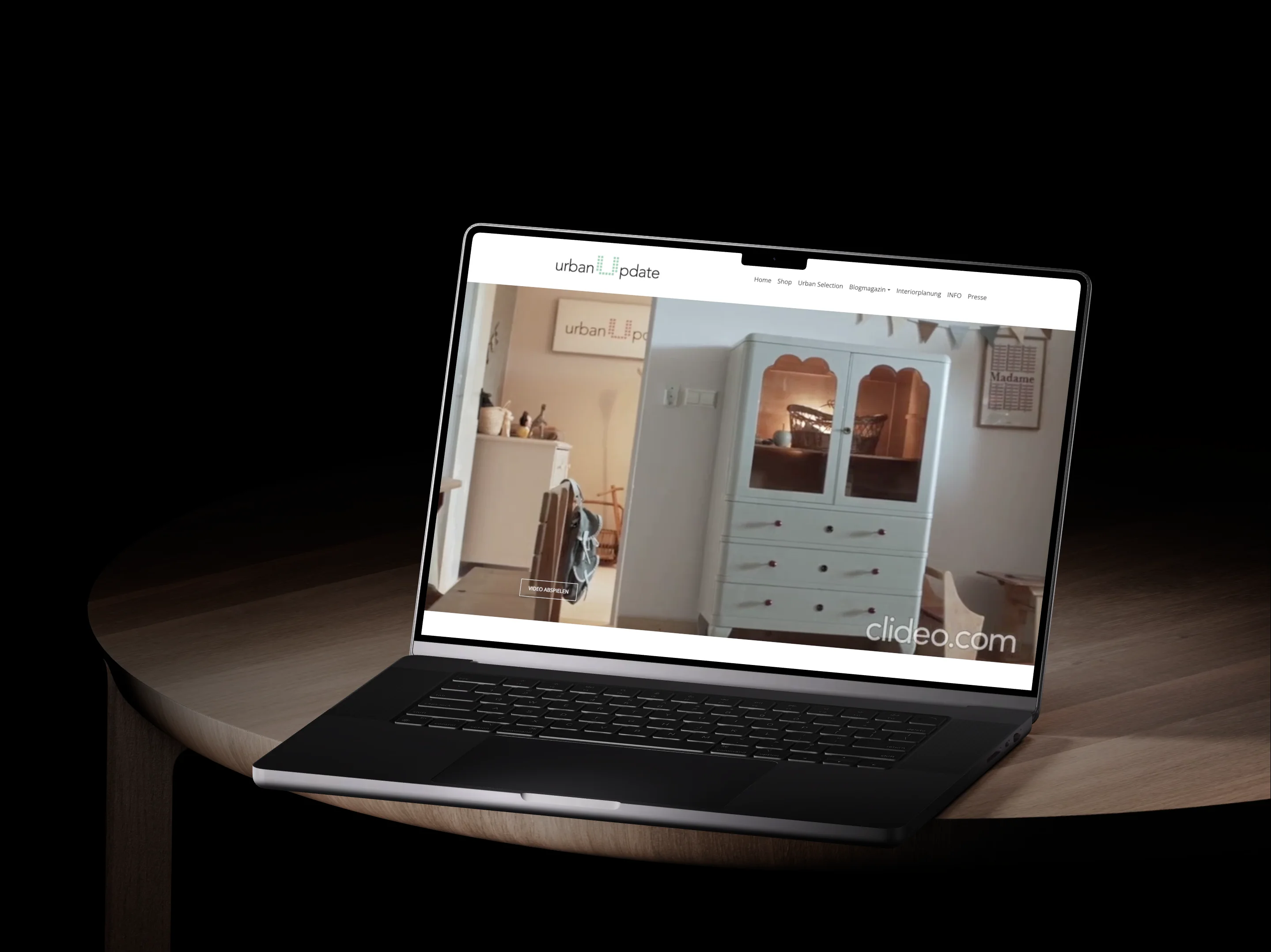 Die alte urbanupdate.at auf einem MacBook: die Startseite mit dem Logo, der Menüzeile und dem Heldenvideo eines hellblauen Vitrinenschranks.