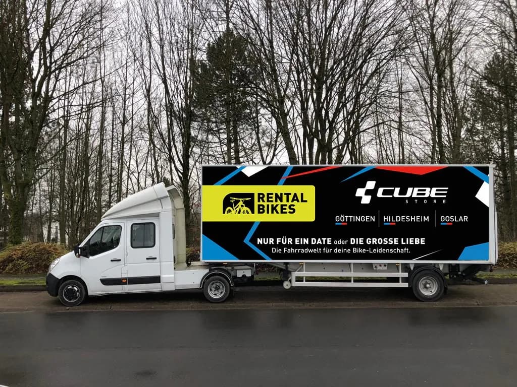 Entwurfsansicht des Bikeliners: ein weißer Lastwagen mit schwarzem Aufbau, darauf das gelbe Label Rental Bikes, der Schriftzug CUBE Store mit den drei Standortnamen und die Zeile Nur für ein Date oder die große Liebe.