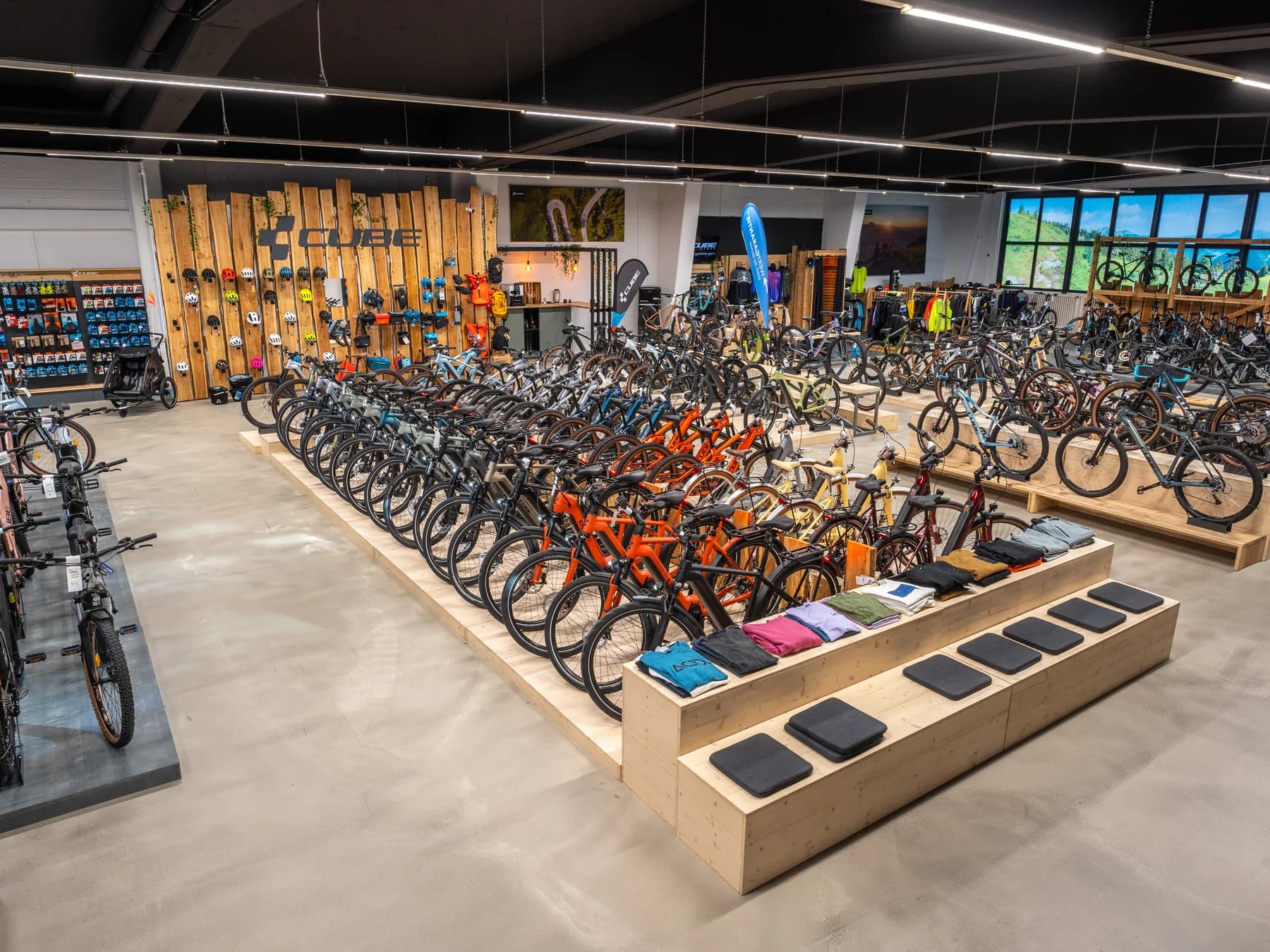 Verkaufsfläche des CUBE Store Hildesheim: lange Reihen aufgereihter Räder auf hölzernen Podesten, dahinter eine Wand mit Zubehör und Bekleidung.