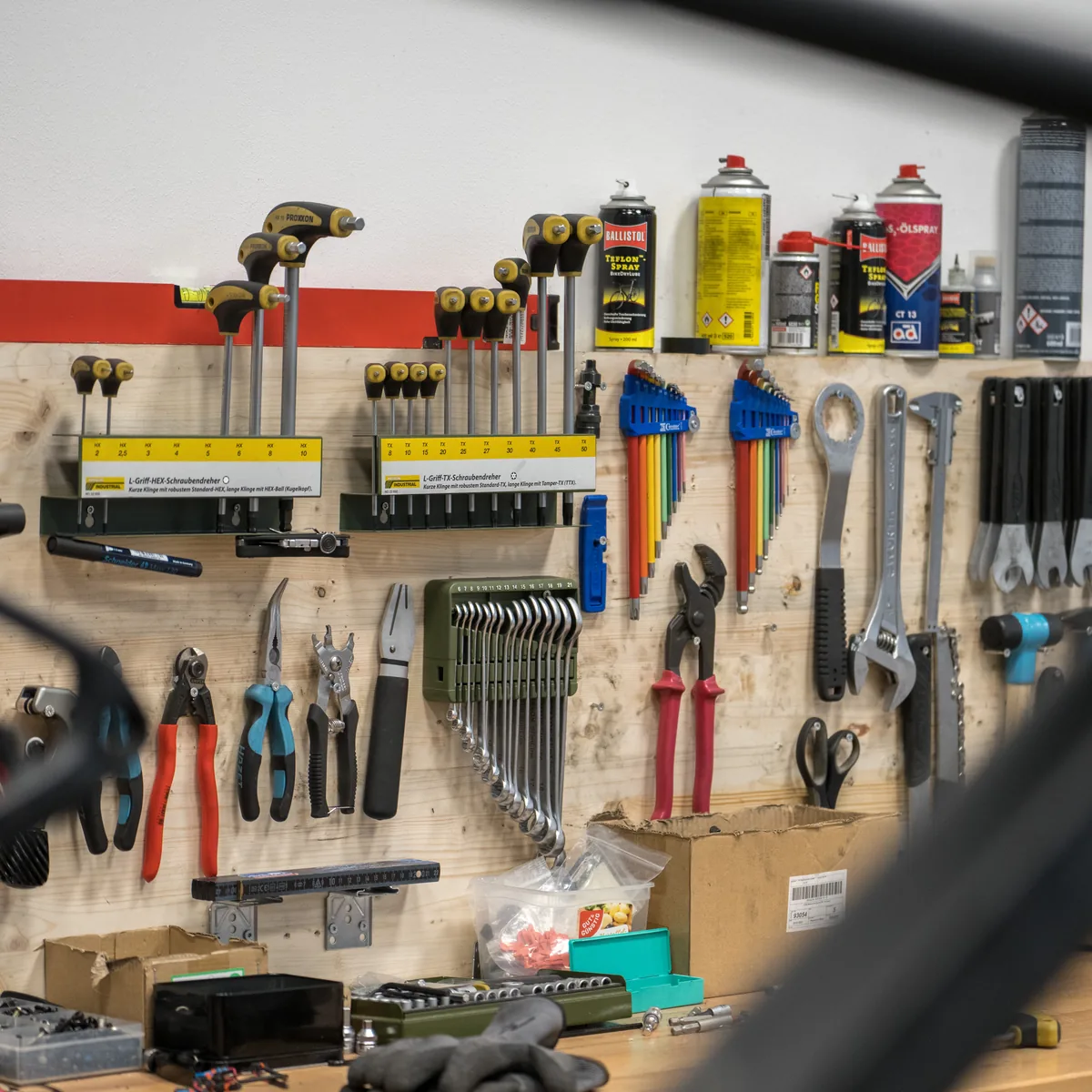 Werkstatt des CUBE Store Hildesheim: eine Wand mit Zangen, Schlüsseln und Schmiermitteln, im Vordergrund unscharf das Rohr eines Rahmens.