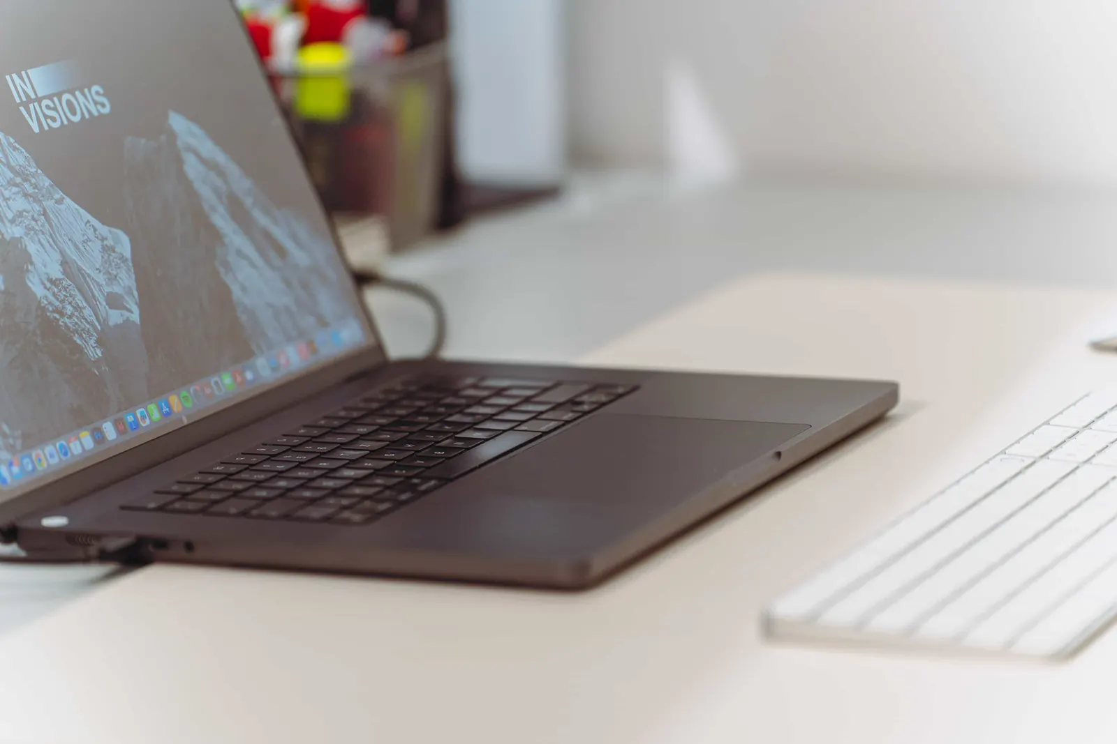 Arbeitsplatz bei Invisions in Innsbruck: aufgeklapptes MacBook mit dem Invisions-Logo auf dem Bildschirm.