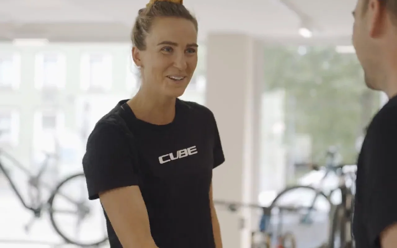 Ausschnitt aus dem Verkaufsfilm: eine Mitarbeiterin im CUBE-Shirt berät einen Kunden an einem Rennrad auf der Verkaufsfläche.