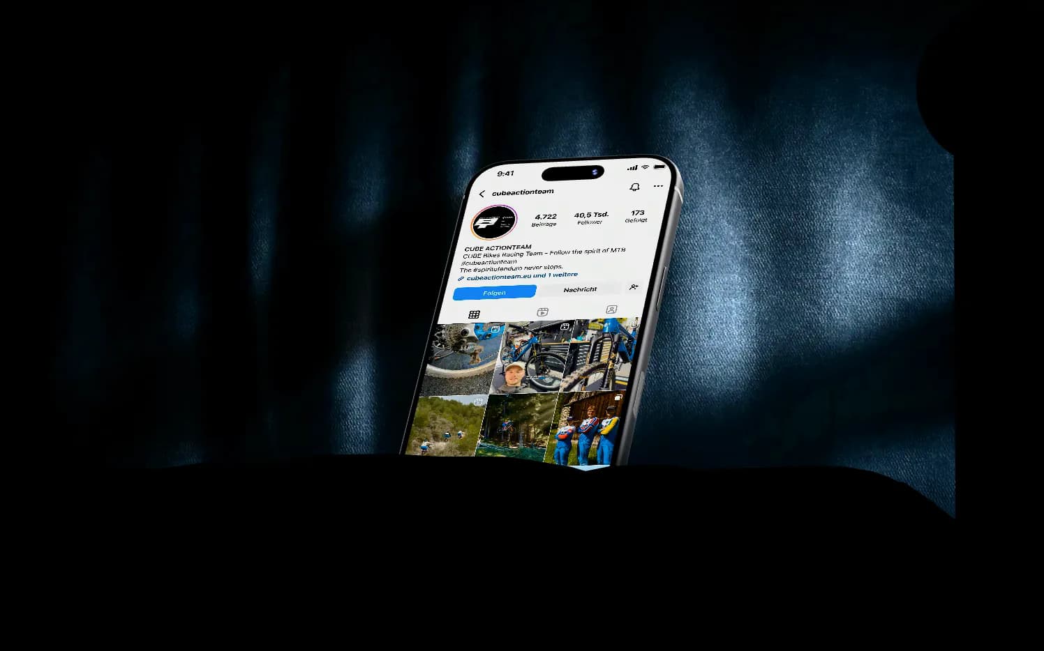 Ein iPhone auf dunklem Stoff zeigt das Instagram-Profil des CUBE Actionteams: erst das Profil, dann das gescrollte Beitragsraster, dann zwei laufende Reels.