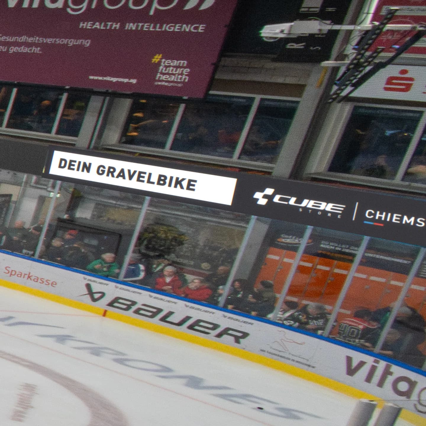 Die LED-Bande über dem Eis im ROFA-Stadion mit der Animation für den CUBE Store Chiemsee, montiert in ein Foto vom Sponsoring Day: die Zeile Dein Gravelbike und das Logo des Stores.