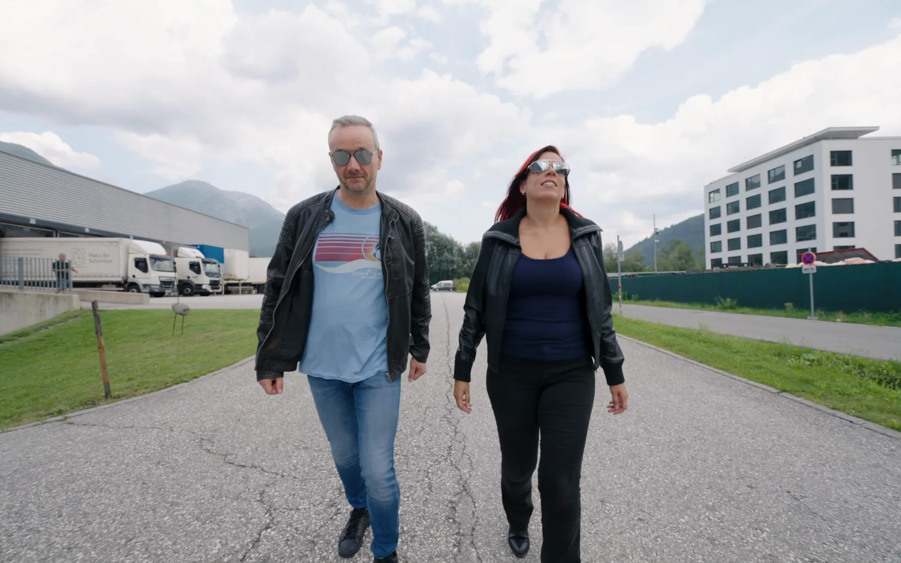 Ausschnitt aus Folge 6: Sara und ihr Kollege Martin gehen über das Gelände, ziehen Arbeitshandschuhe an, setzen Schutzbrille und Gehörschutz auf und machen sich bereit, eine Stromschiene zu schneiden.