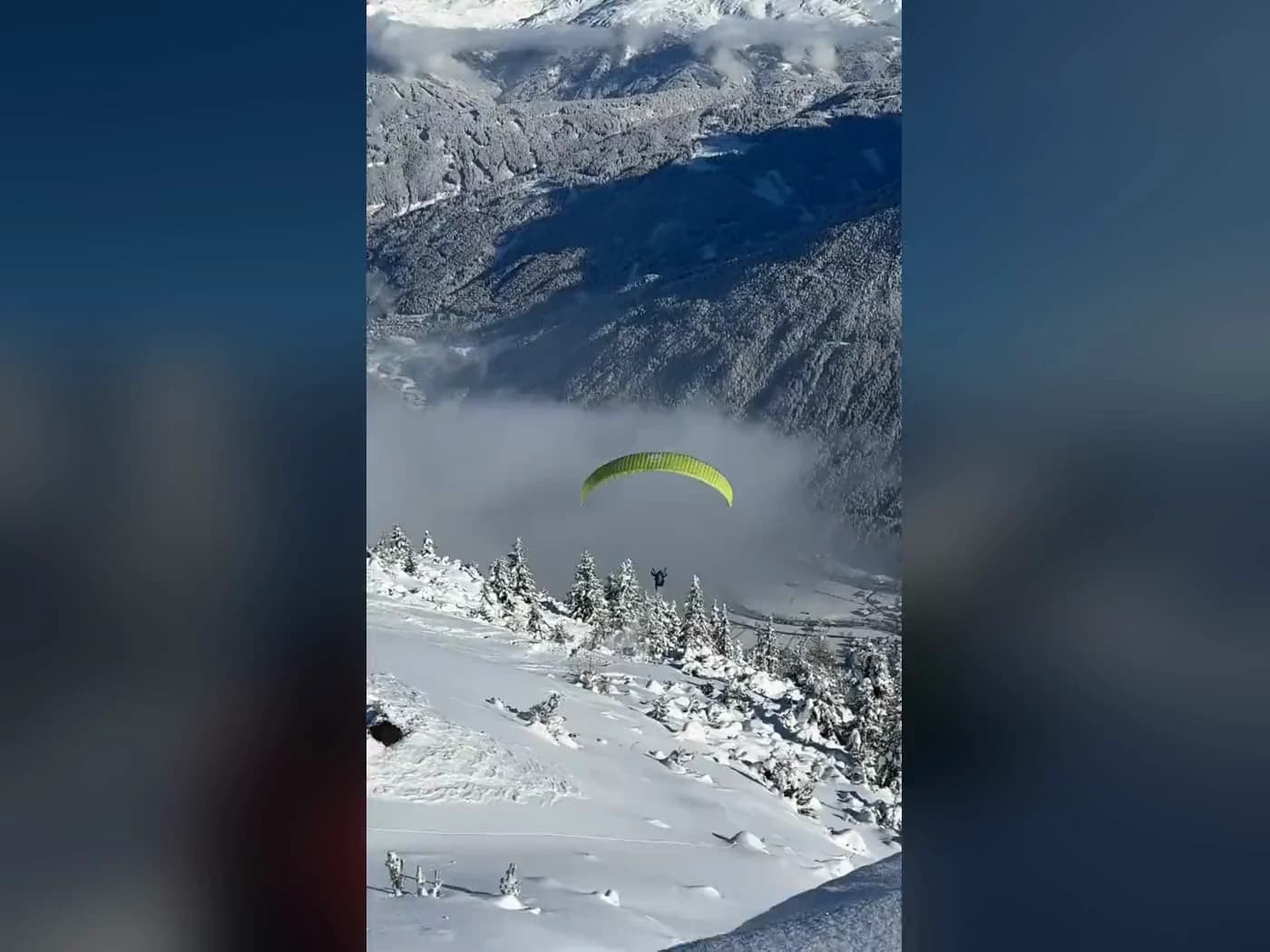 Das Standbild des Winter-Reels im Hochformat: ein Gleitschirm über dem verschneiten Hang, im Hintergrund die Berge.