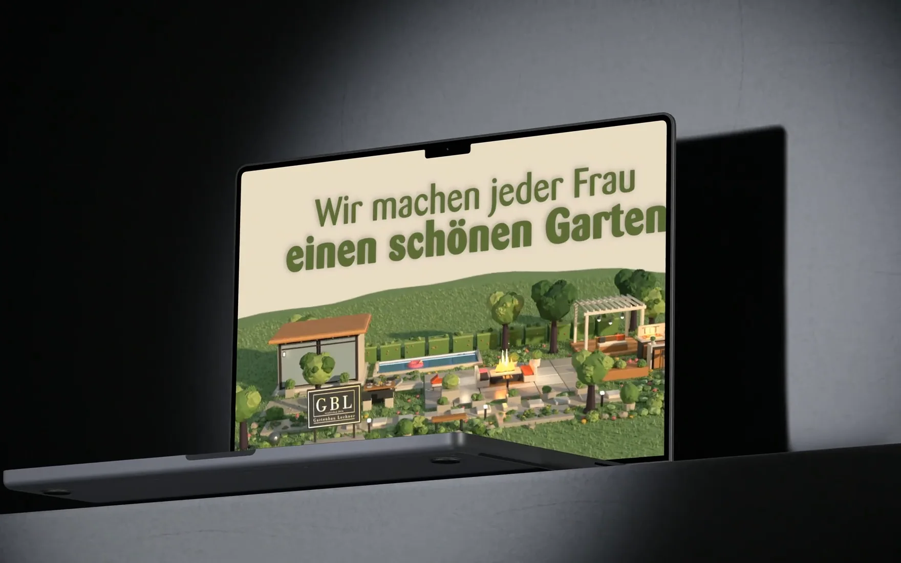 Der Werbespot für Gartenbau Lechner auf einem MacBook, das schräg auf einer dunklen Ablage im Lichtkegel vor einer grauen Wand steht: auf dem Bildschirm entsteht der 3D-Garten, dann folgen Slogan, Marke und Adresse.
