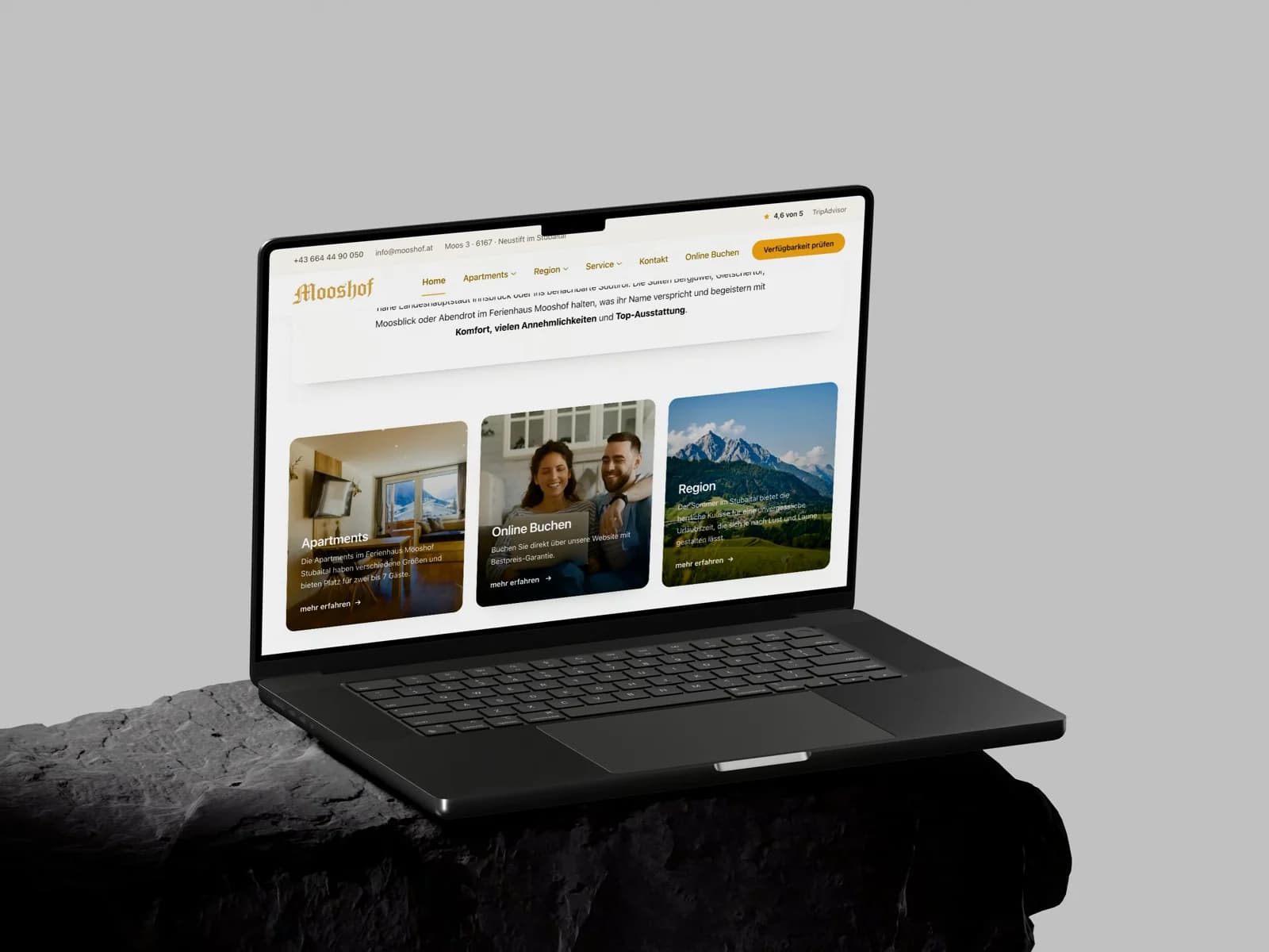 Ein MacBook Pro auf einem Stein klappt auf und zeigt die Startseite von mooshof.at, die von oben nach unten durchläuft.