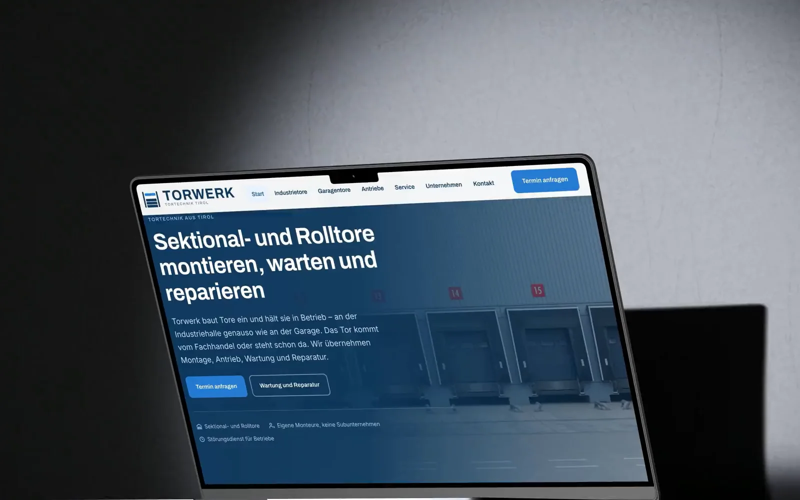 Eine Kamerafahrt um ein MacBook im dunklen Studio: auf dem Bildschirm läuft die Startseite von torwerk.at vom Seitenkopf mit den Verladetoren bis zum Fuß durch.