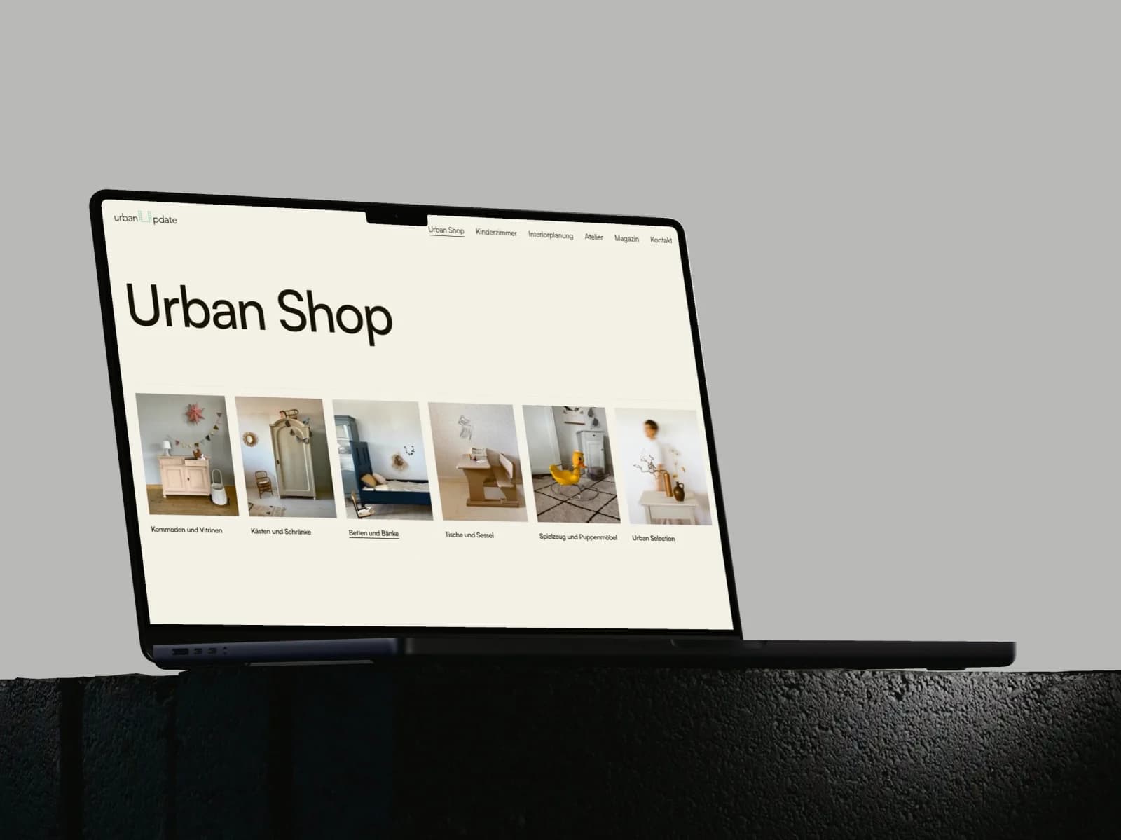 Ein MacBook Pro klappt auf und zeigt den Urban Shop von UrbanUpdate mit den sechs Kategoriekacheln, danach fährt die Seite zum Band Neu im Shop mit vier aufgearbeiteten Stücken.