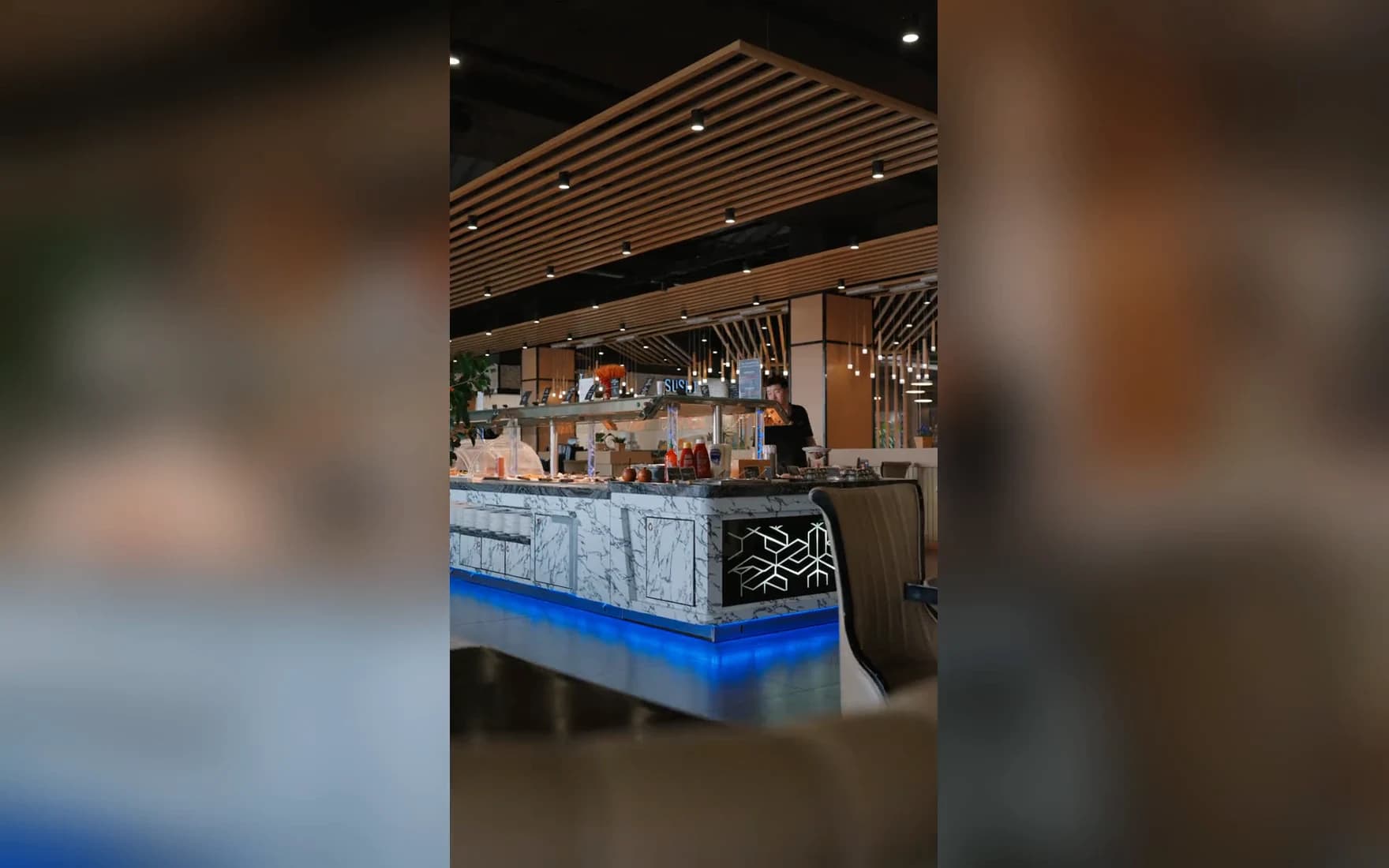 Ein Rundgang durch das Asia Restaurant YAMI: der Gastraum unter der Holzlattendecke, die Theke mit dem blauen Lichtband, ein Koch am Teppanyaki-Grill und die Wok-Pfanne.