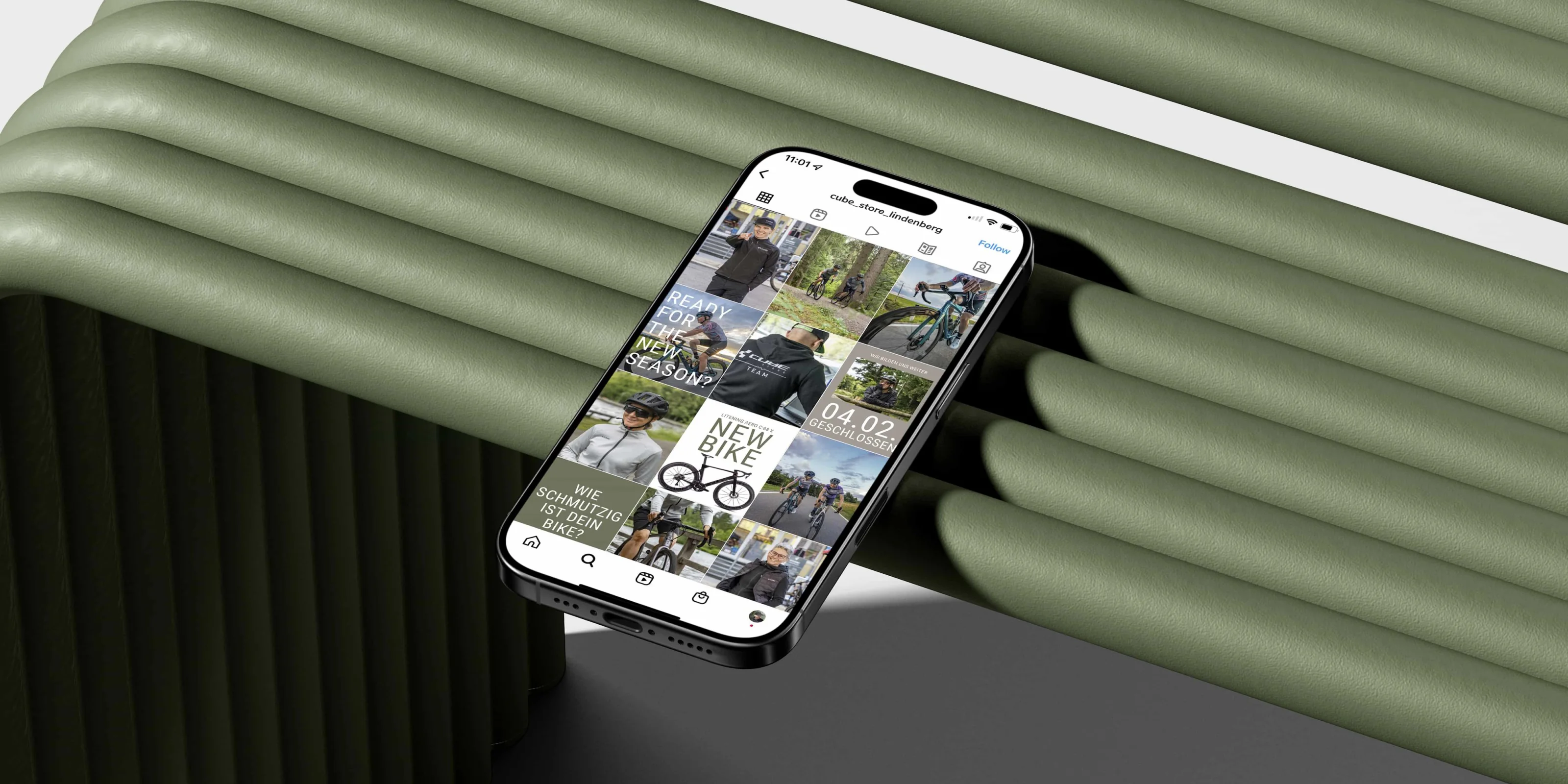 CUBE Store Lindenberg: Ein Telefon auf einer salbeigrünen Bank zeigt das Instagram-Profil des Stores mit dem gestalteten Beitragsraster.