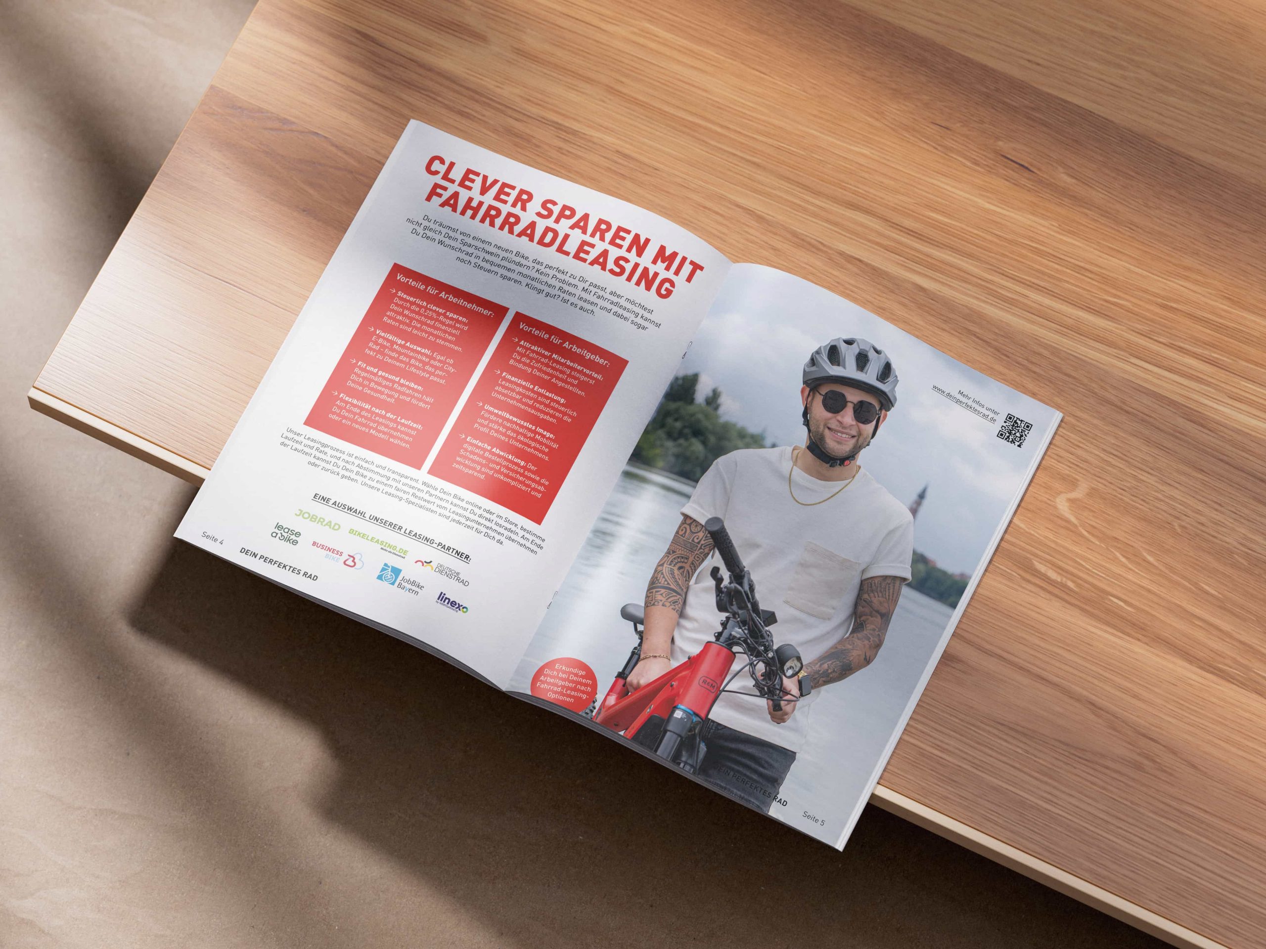 Eine aufgeschlagene Zeitschrift auf einem Holztisch zeigt eine Seite mit einem Mann mit Helm und Sonnenbrille, der ein rotes Fahrrad hält, und einen deutschen Text über das Sparen mit Fahrradleasing.