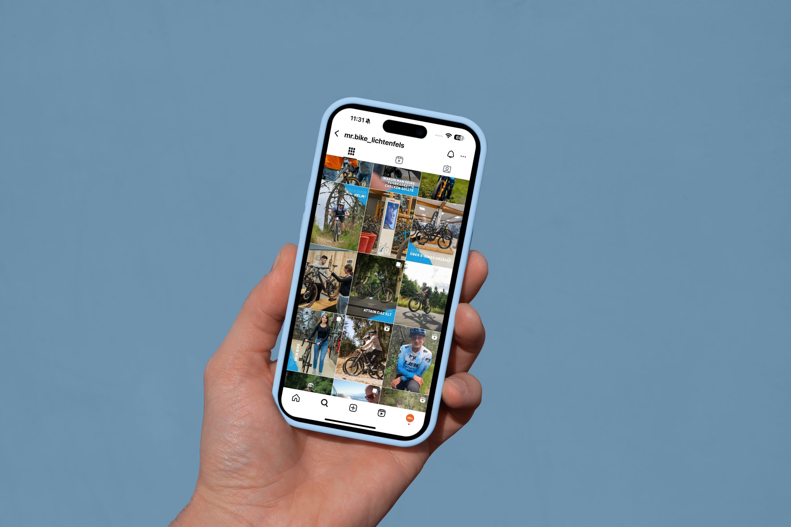 Eine Hand hält ein Smartphone, auf dem ein Instagram-Profil mit einer Reihe von Fotos zu sehen ist, die meist Fahrräder und eine Person im Freien vor einem einfarbig blauen Hintergrund zeigen.