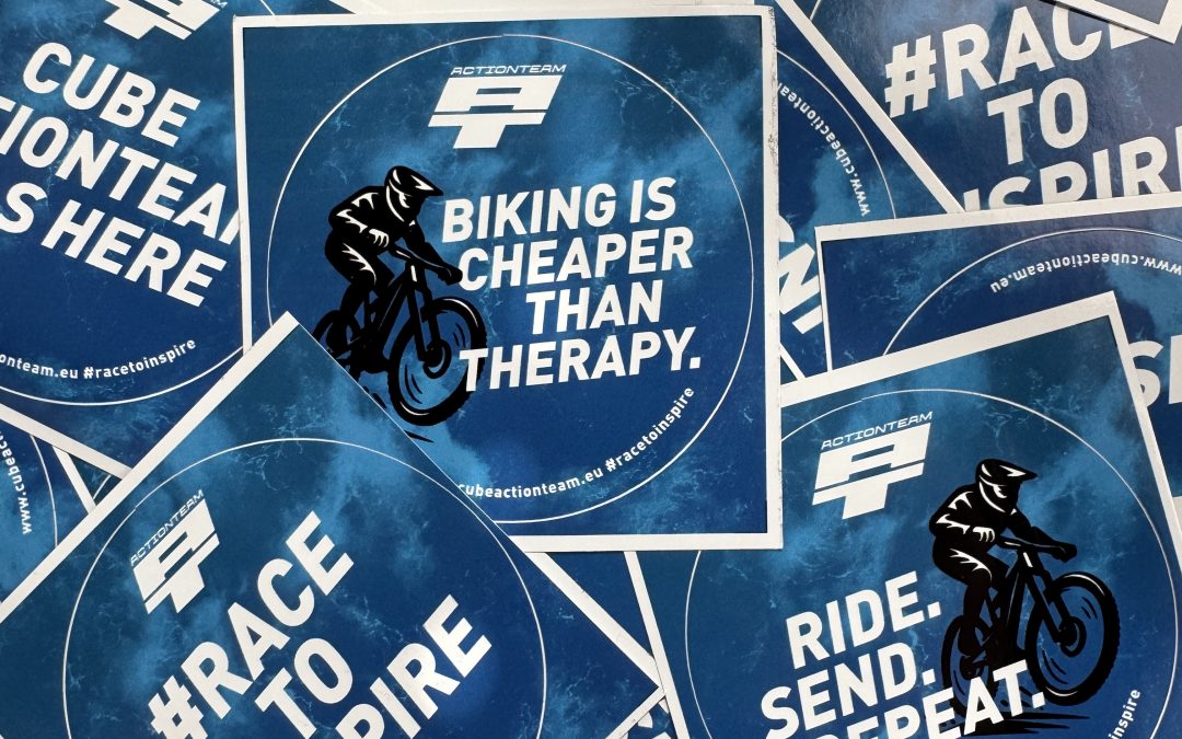 Ein Stapel blauer kreisförmiger Aufkleber mit motivierenden Radsport-Slogans wie "BIKING IS CHEAPER THAN THERAPY", "#RACE TO INSPIRE" und "RIDE. SENDEN. REPEAT." Auf einigen Aufklebern ist ein Radfahrer abgebildet.