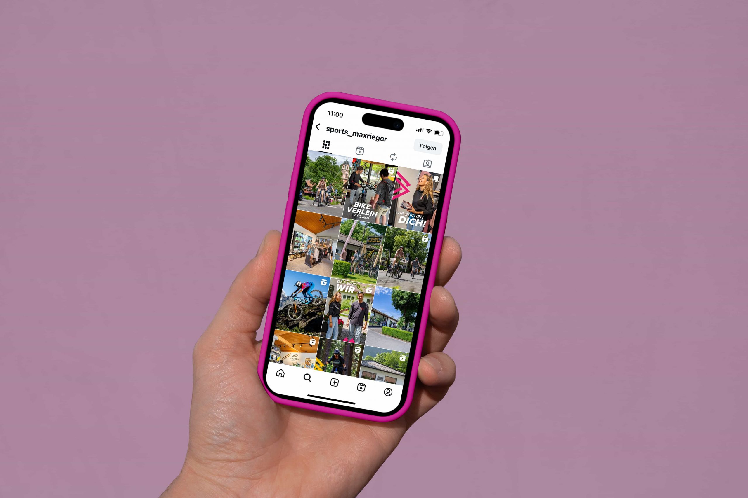 maxrieger_SM_MockUp Eine Hand, die ein Smartphone mit rosa Gehäuse hält, zeigt ein Instagram-Profil mit einem Raster von Sport- und Outdoor-Fotos vor einem schlichten lilafarbenen Hintergrund.