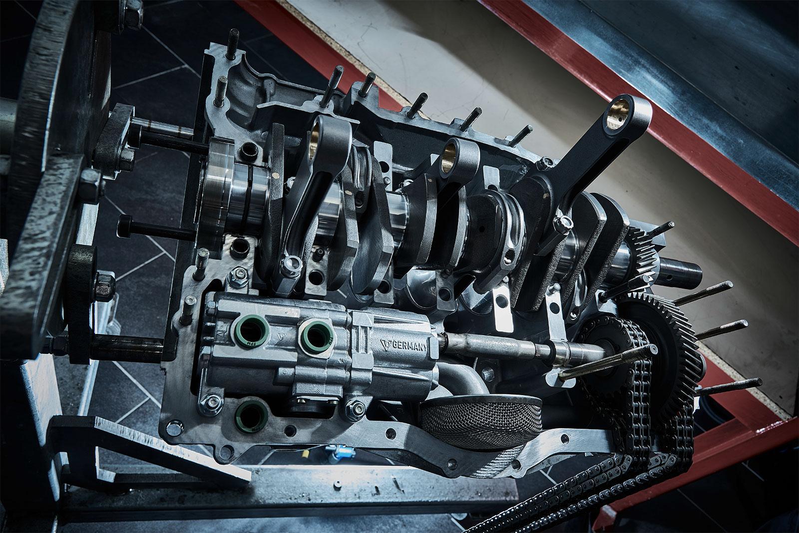 Nahaufnahme eines teilweise montierten Automotors mit Kurbelwelle, Pleuelstangen und verschiedenen internen Komponenten auf einer Werkbank.