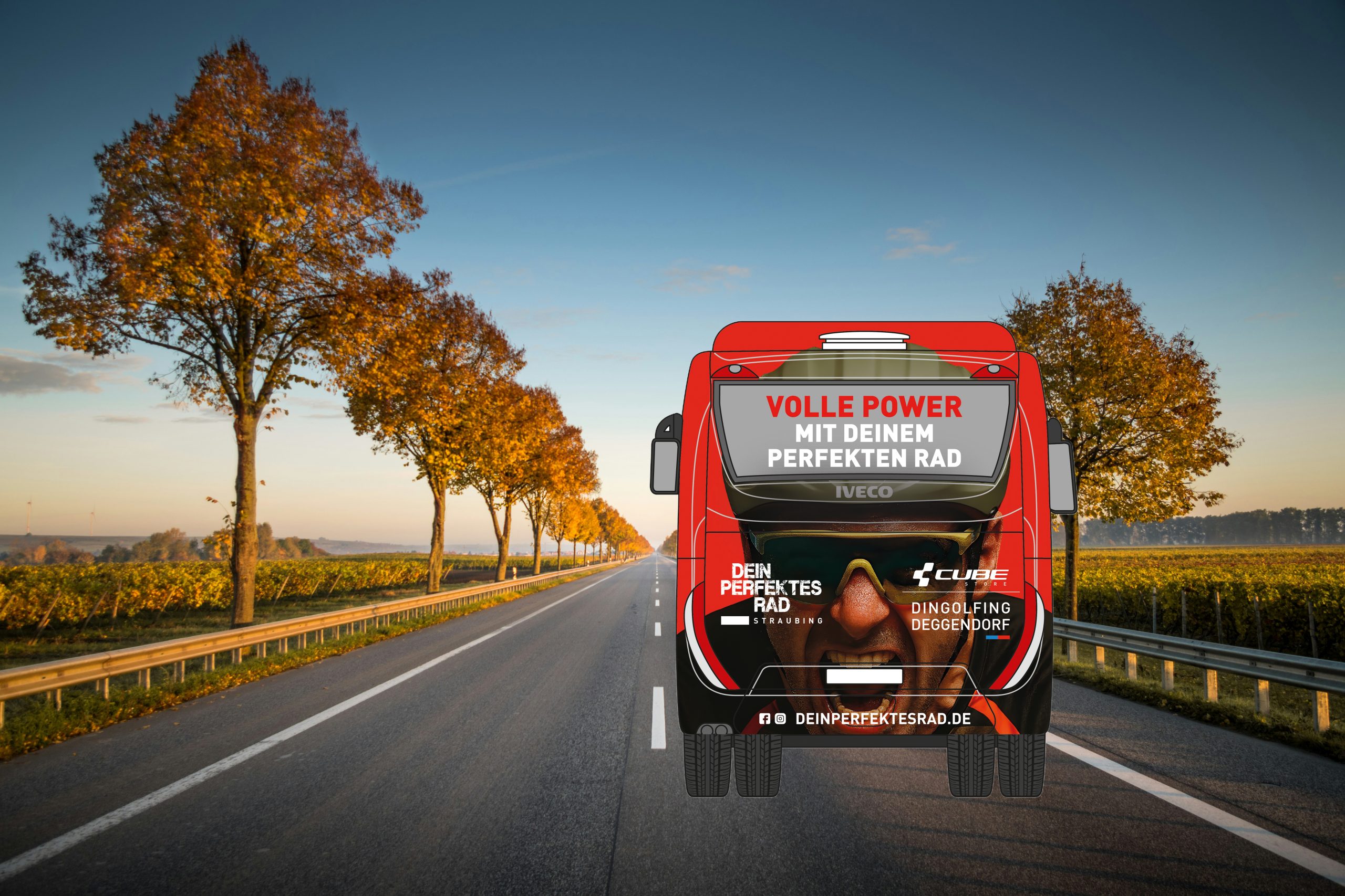 Ein roter Bus fährt bei Sonnenaufgang oder Sonnenuntergang eine leere, von Bäumen gesäumte Straße entlang. Auf der Rückseite des Busses sind deutsche Texte und Bilder zu sehen, die für Fahrräder werben. Der Himmel ist klar, und warmes Sonnenlicht erhellt die Szene.