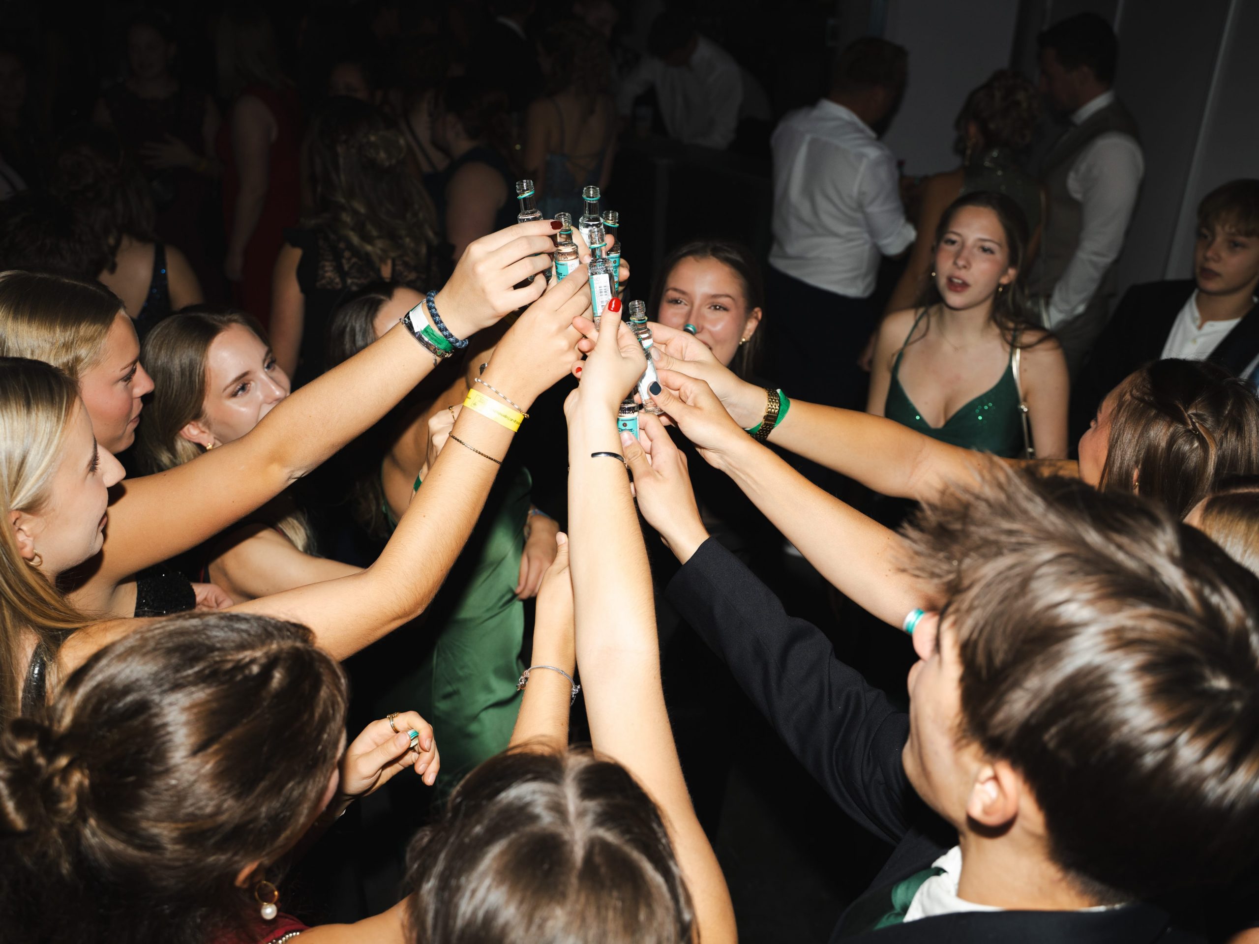 Eine Gruppe formell gekleideter junger Leute stößt auf einer lebhaften Party oder Feier mit einem Lächeln an und genießt den Moment.